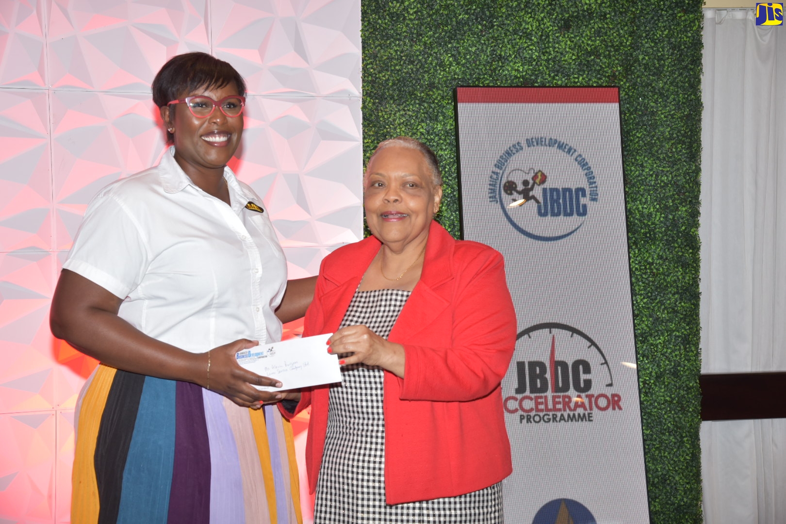 Chief Executive Officer, Jamaica Business Development Corporation (JBDC), Valerie Veira (right), presents Alecia Burgess, representing Lama Services Company Limited, with documents formalising participation in the JBDC’s Accelerator Programme, at the official launch for cohort four, held at The Jamaica Pegasus hotel in New Kingston, on April 5.