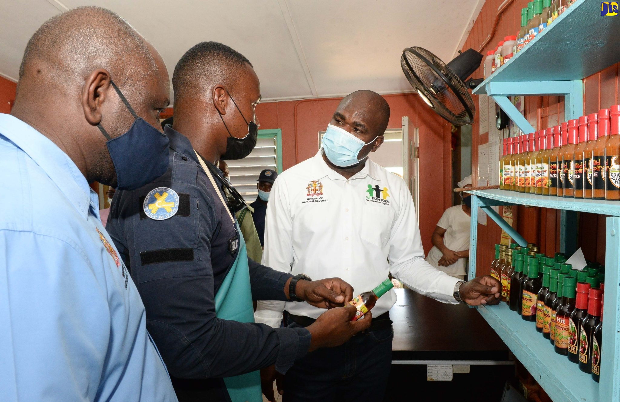 Minister of State in the Ministry of National Security, Hon. Zavia Mayne (right), speaks with Correctional Officer, Michael Harris (centre), about the sauces and wines made by inmates at the St. Catherine Adult Correctional Centre, during a tour of the facility in Spanish Town on Friday (April 8). Also on the tour was Permanent Secretary in the Ministry, Courtney Williams (left).