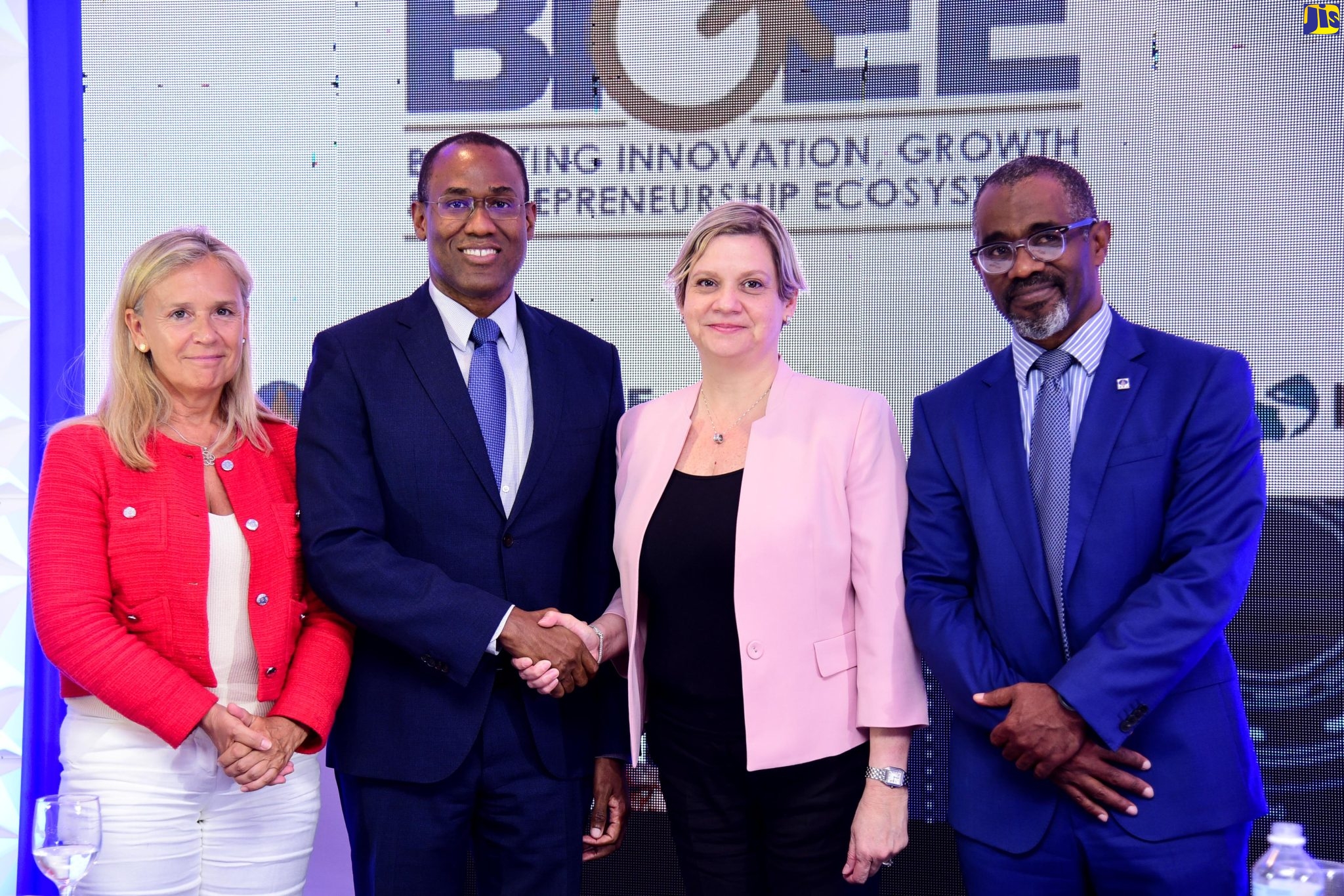 Minister of Finance and the Public Service, Dr. the Hon. Nigel Clarke (second left), and General Manager (Acting), Inter-American Development Bank (IDB) Caribbean Country Department Group, Carmen Madriz, shake hands after the symbolic signing of a Non-Reimbursable Agreement for the European Union’s provision of a €7-million (over J$1.2-billion) grant for the Government’s Boosting Innovation, Growth and Entrepreneurship Ecosystems (BIGEE) Programme. The signing was held during a Visibility Ceremony at The Jamaica Pegasus hotel in New Kingston, on Wednesday (May 25). With them (from left) are Head of the European Union Delegation in Jamaica, Ambassador Marianne Van Steen; and Managing Director of the Development Bank of Jamaica (DBJ), which is implementing the BIGEE Programme, Anthony Shaw.  