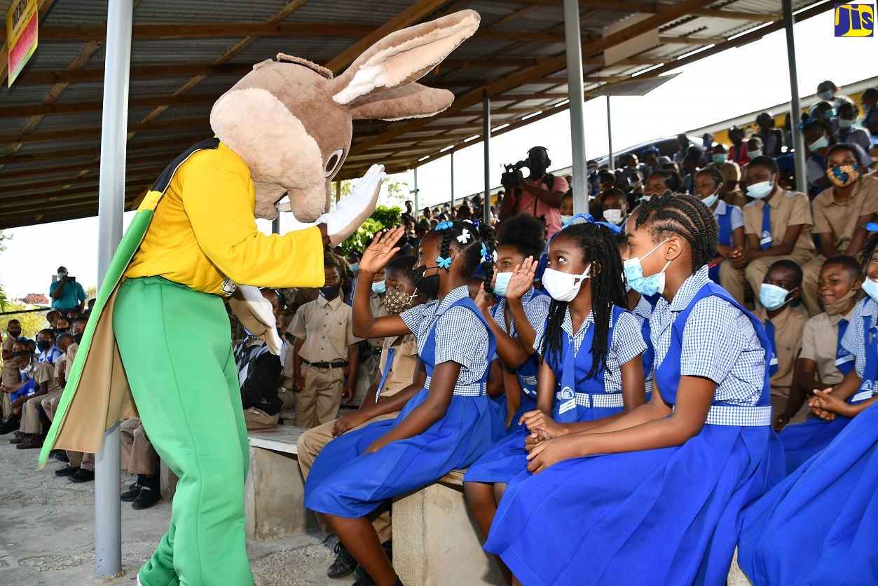 The Child Protection and Family Services Agency (CPFSA) mascot, ‘Mr. Protector’ (left), interacts with students of the Bamboo Primary and Junior High School in St. Ann during a school tour on Tuesday (May 3) to promote the importance of child protection and the Agency’s 211 Child Abuse Reporting Hotline.  