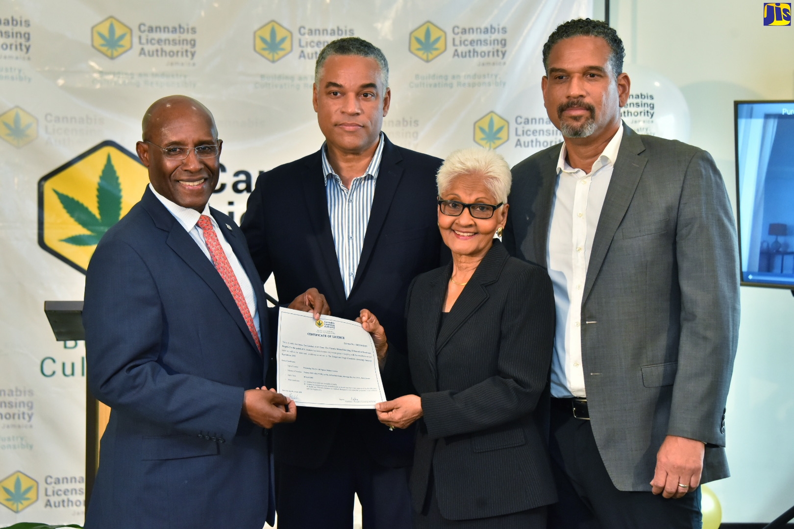 Minister of Industry, Investment and Commerce, Senator the Hon. Aubyn Hill (left), presents the 100th licence for the Medicinal and Therapeutic Handling of Cannabis in Jamaica, to Board Director of Seven-10 Limited, Mrs. Hyacinth Symes, at a ceremony  hosted by the Cannabis Licensing Authority, at the Courtyard by Marriott Hotel, in Kingston, on May 11. Sharing the moment (from second left) are Board Director of Seven-10 Limited’s parent-company, Pure Jamaican, Robert Wright and Board Director at Seven-10, Brian Wright.