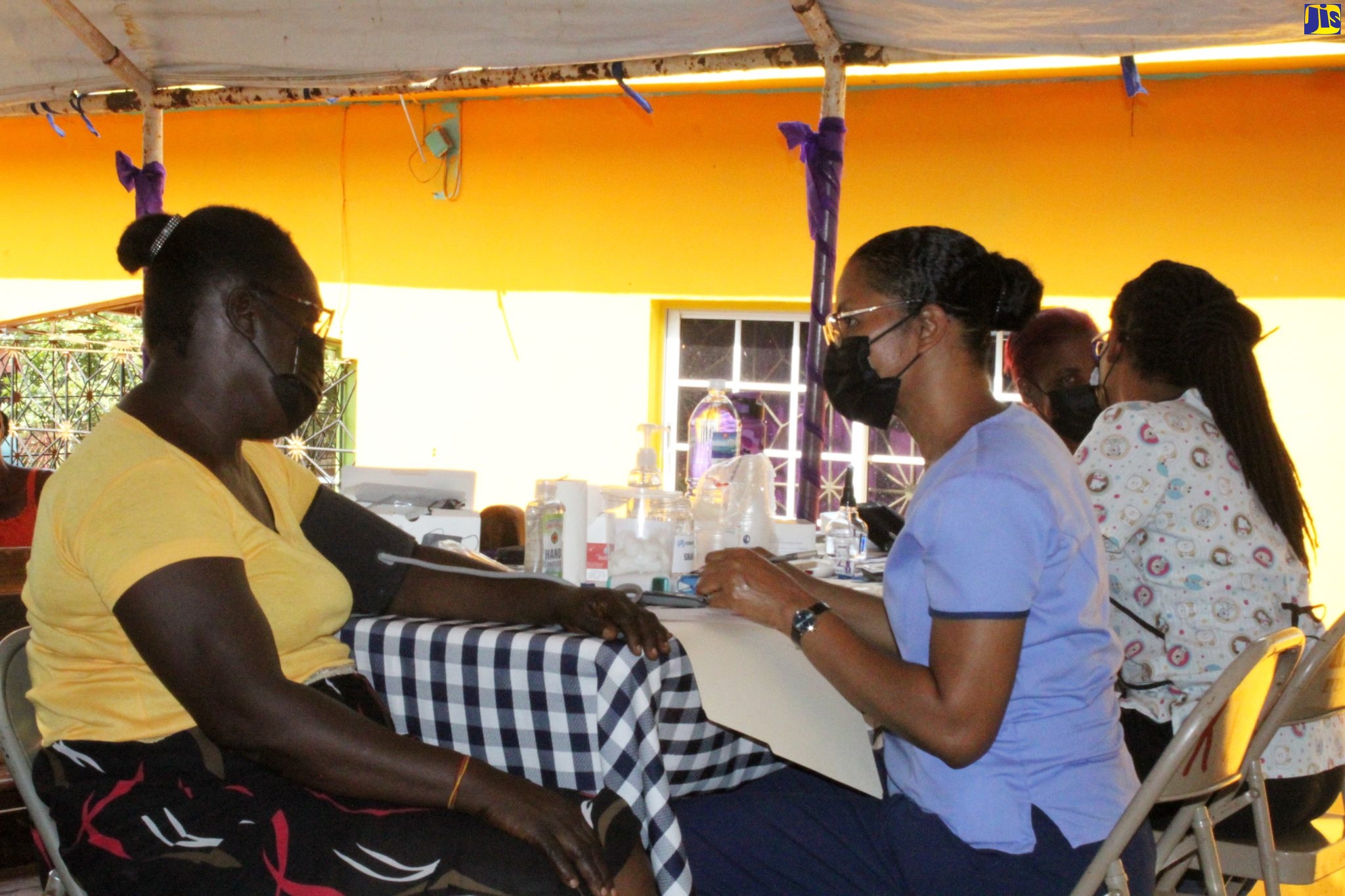 Health Ministry Director at the Kitson Town Seventh-day Adventist (SDA) Church, Ann-Marie Brown (second left), attends to a member of the Cottage community in St. Catherine, during the staging of a free health clinic in the area on Sunday (May 15).