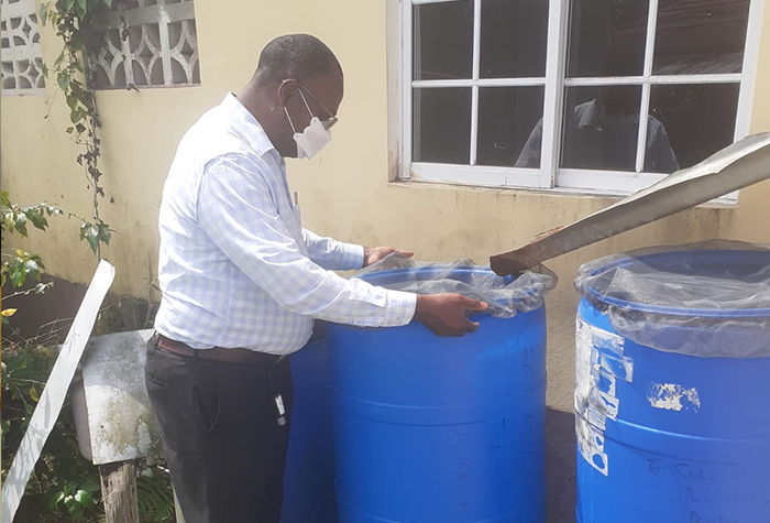 Health Promotion and Education Officer at the Westmoreland Public Health Department, Gerald Miller, puts on a water drum cover during a visit to the Rose Hill community in the parish, recently. 