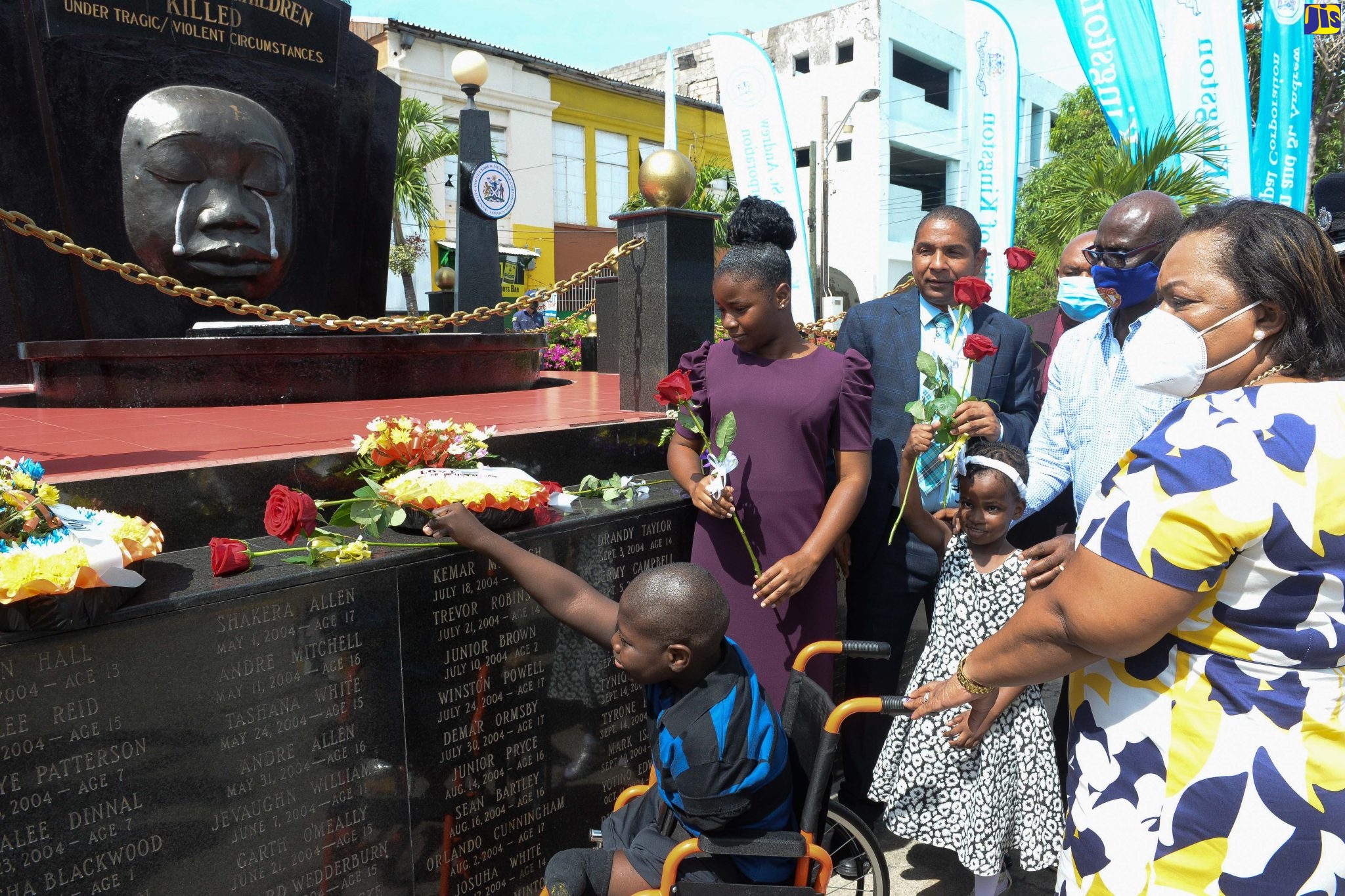 Minister of Local Government and Rural Development, Hon. Desmond McKenzie (second right), and Chief Executive Officer, Child Protection and Family Services Agency, Rosalee Gage-Grey (right), look on as DeAndre Simpson (left) places a rose at the Secret Gardens Monument in downtown Kingston on Sunday (May 1) in memory of the nation’s children who have died under tragic/violent circumstances. The month of May is being observed as Child Month under the theme ‘Listen Up! Children’s Voices Matter’.  Also preparing to lay floral tributes (from second left) are Aisha Marriot; Youth Mayor of Kingston, Raejean Bennett; Mayor of Kingston, Senator Councillor Delroy Williams; and Deputy Mayor, Councillor Winston Ennis (partially hidden).