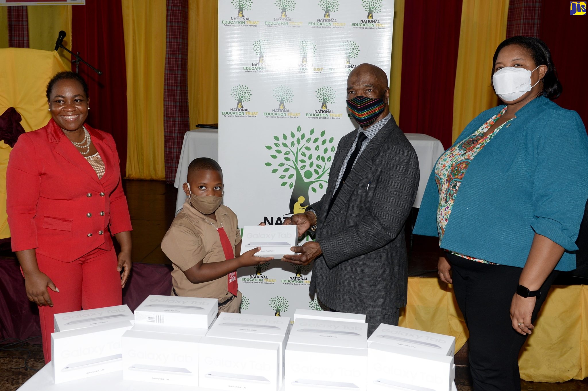 Donor of 586 tablets to students from schools in St. Thomas and St. Catherine, Melvin McDonald (second right), presents one of the items to student from Marlie Hill Primary and Infant School, Jayeshawn Douglas (second left), during a handover ceremony. Looking on are (from left) Region Six Director, Sophia Forbes Hall and Region Two Director, Yashieka Blackwood-Grant. The ceremony was held at Dinthill Technical High School in St. Catherine on Tuesday (May 17).