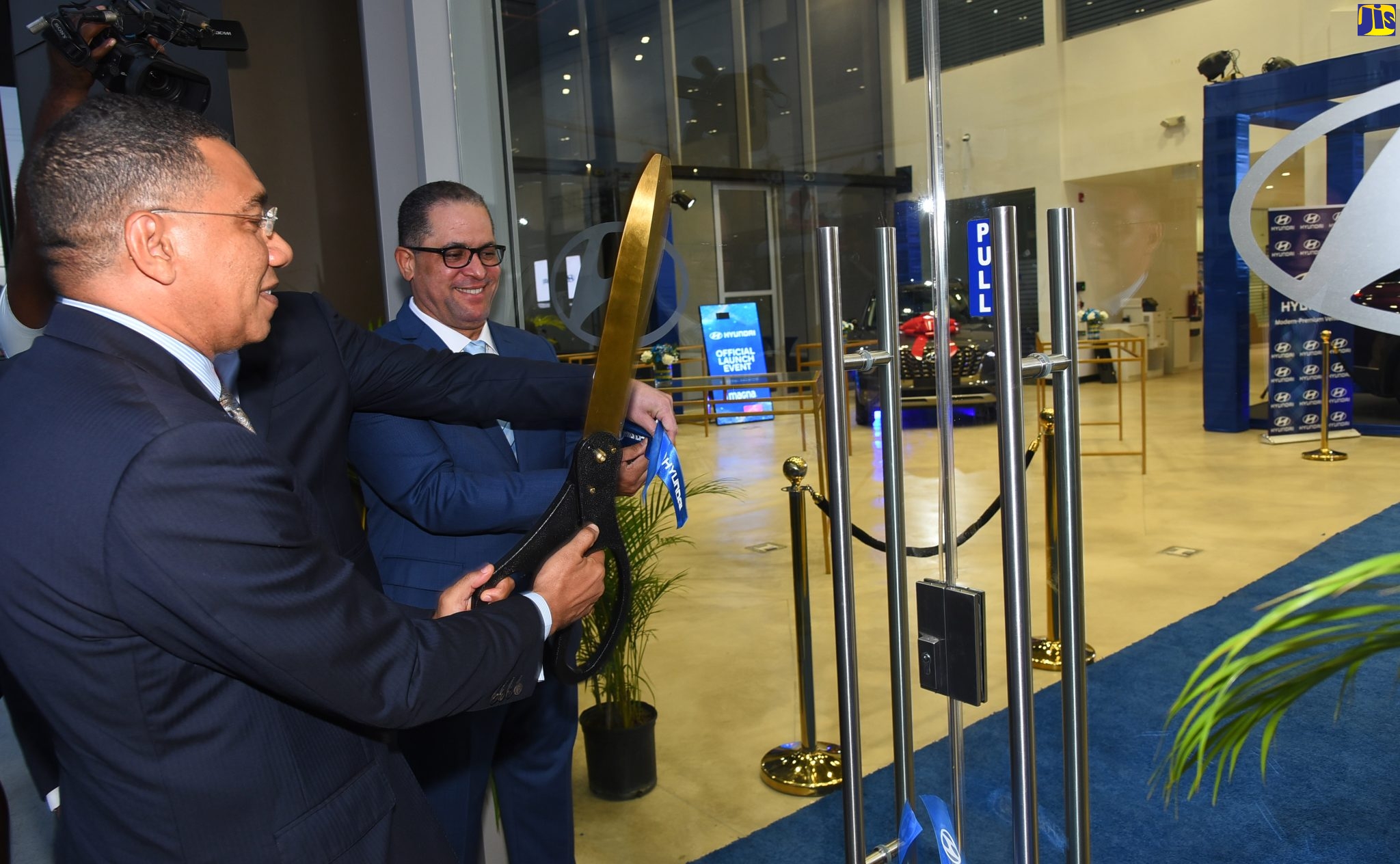 Prime Minister, the Most Hon. Andrew Holness, cuts the ribbon to officially launch Magna Motors Dealership Limited’s (Hyundai) new state-of-the-art facility and seventh anniversary celebrations, at the entity’s Oxford Road address, St. Andrew, on Thursday (May 12). Looking on is Chief Executive Officer (CEO), Magna Motors Dealership (Jamaica), Erick Gutierrez.