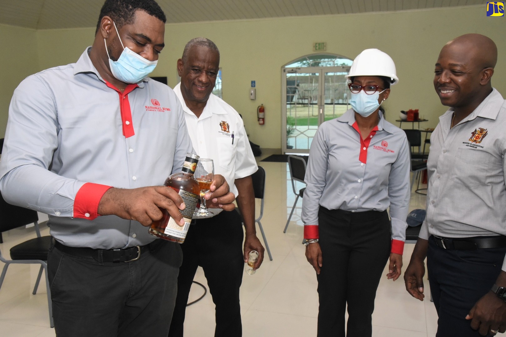 Agriculture and Fisheries Minister, Hon. Pearnel Charles Jnr (right), observes as National Rums of Jamaica Limited Group Operations Manager, Michael Dunkley (left), pours a product sample during a visit to Clarendon Distillers Limited on Friday (May 27). Also looking on are State Minister in the Ministry of Agriculture, Hon. Franklin Witter (second left); and Chief Executive Officer, National Rums of Jamaica, Martha Miller.