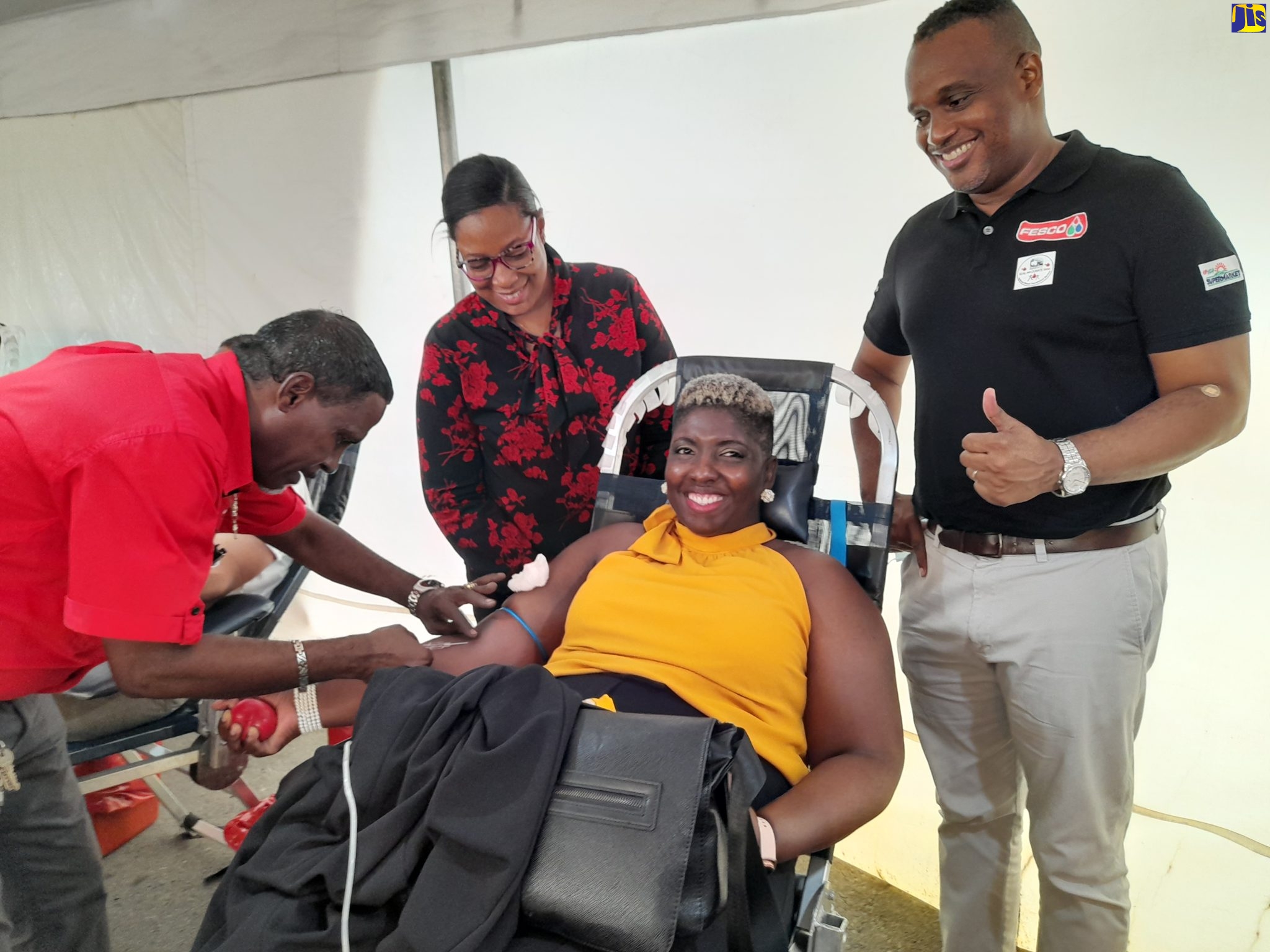 Technical Assistant at the National Blood Transfusion Service, Christopher Copeland (left), performs a blood collection on Director of the Jamaica Gasolene Retailers