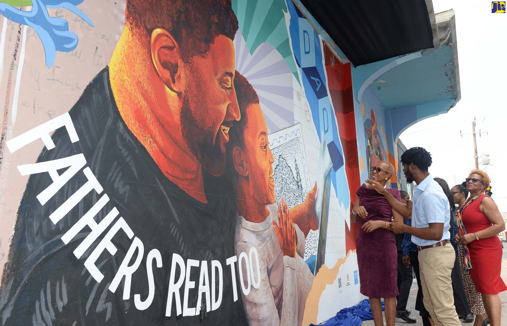 Minister of Education and Youth, Hon. Fayval Williams listens as artist, Anthony Smith explains intricacies of the artwork in tribute to fathers, following its official unveiling along Church Street, downtown Kingston on Father’s Day (June 19). The mural is part of the