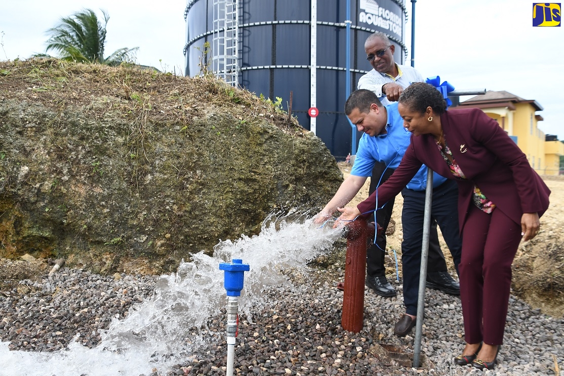 Minister without Portfolio in the Ministry of Economic Growth and Job Creation, Senator the Hon. Matthew Samuda (centre), wets his hand after commissioning the $30-million West Gate Hills number two storage replacement tank into service during a ceremony held at West Gate Hills Boulevard, Montego Bay, St. James, on Thursday, June 16. He is joined by Member of Parliament for West Central St. James, Marlene Malahoo-Forte.  Looking on is Water Production Manager at the National Water Commission in St James, Fitzgerald Roach.