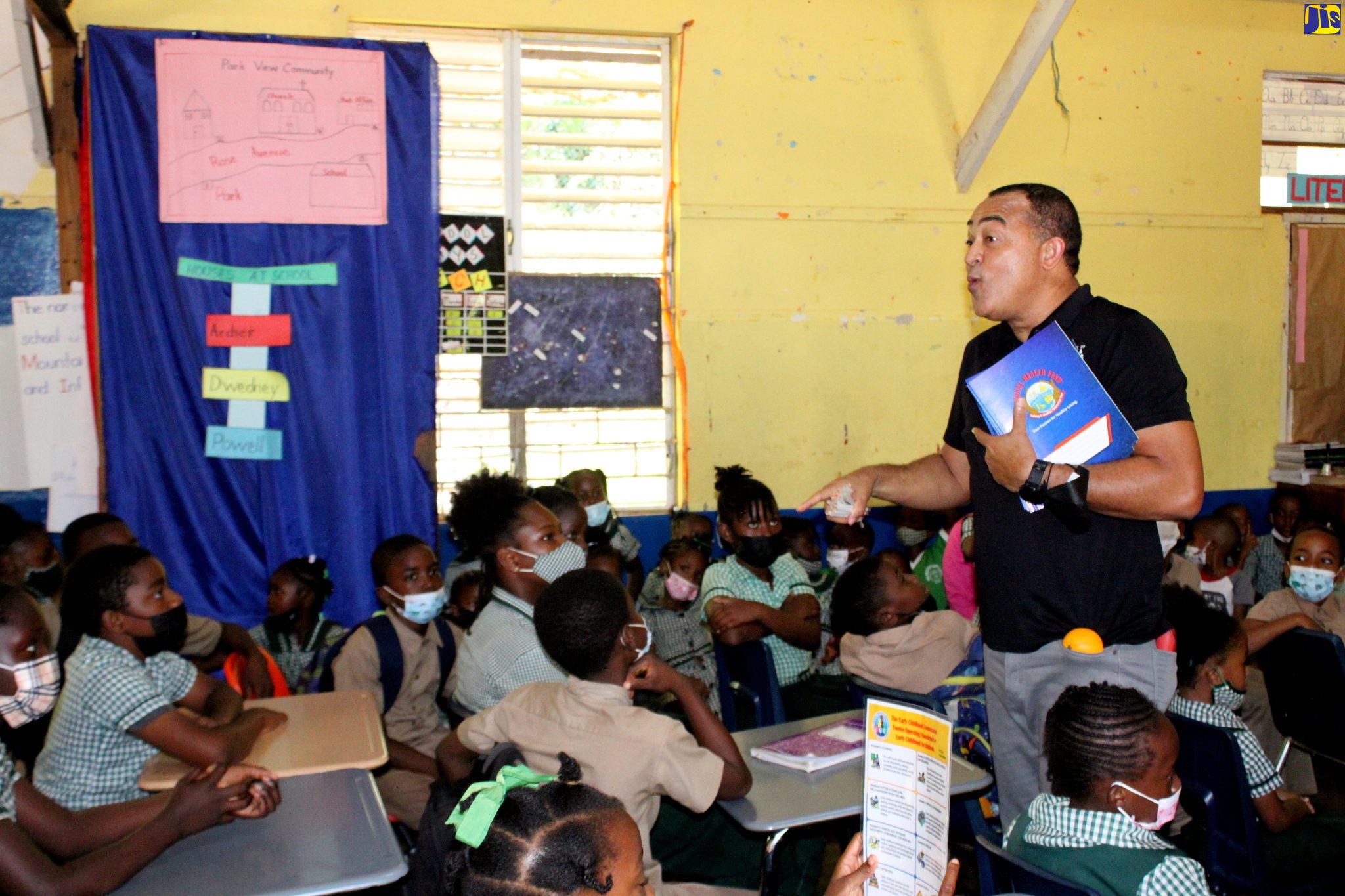 Minister of Health and Wellness, Dr. the Hon. Christopher Tufton (standing), engages with students at the Paul’s Mountain Primary School in St. Catherine, during a recent wellness forum at the institution.