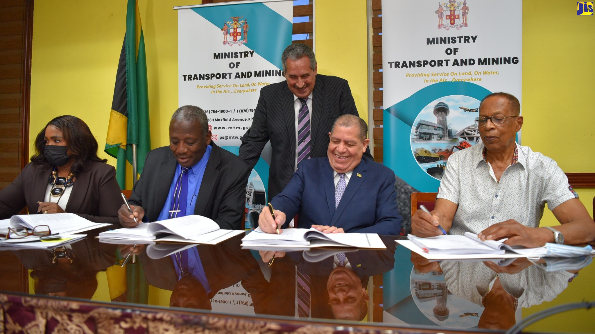 Minister of Transport and Mining, Hon. Audley Shaw (second right); Managing Director, JR Wellington Import and Export Limited, Rennie Wellington (right); and Permanent Secretary in the Ministry of Transport and Mining, Dr. Alwin Hales (second left), affix their signatures to the contract for the procurement of 50 buses to increase the fleet of the Jamaica Urban Transit Company (JUTC), The signing ceremony was held at the Ministry’s Maxfield Avenue offices in St. Andrew on May 31. Observing the signing are Chief Technical Director (Acting) in the Ministry, Dawn Smith Fagan (seated left) and Managing Director, Jamaica Urban Transit Company, Paul Abrahams. 