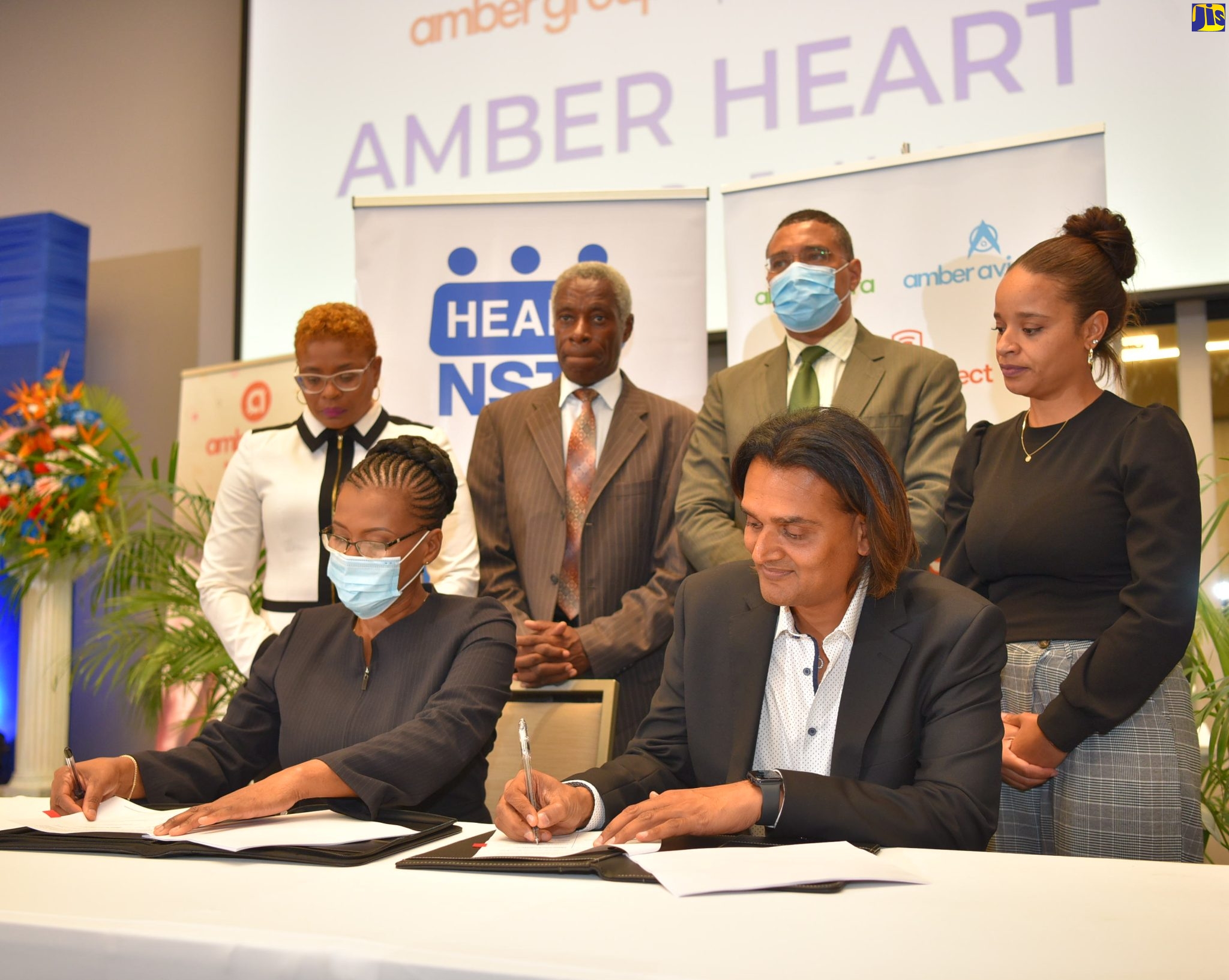 Prime Minister, the Most Hon. Andrew Holness (standing, second right), observes as Founder and Chief Executive Officer (CEO) of the Amber Group, Dushyant Savadia (seated right) and Managing Director (Acting), HEART/NSTA Trust, Novelette Denton Prince (seated left), sign the memorandum of understanding to formalise the partnership for the establishment of the Amber HEART Institute of Coding. Occasion was the graduation ceremony for the first cohort of trainees under the pilot Amber HEART Academy, at the AC Marriott by Kingston in St. Andrew on June 1. Others observing (from left, standing) are Deputy Managing Director (Acting), HEART/NSTA Trust, Kenesha Campbell; Chairman, HEART/NSTA Trust, Professor Alwin Wint; and Executive Assistant to the Founder and CEO, Amber Group, Juliana Moodie.