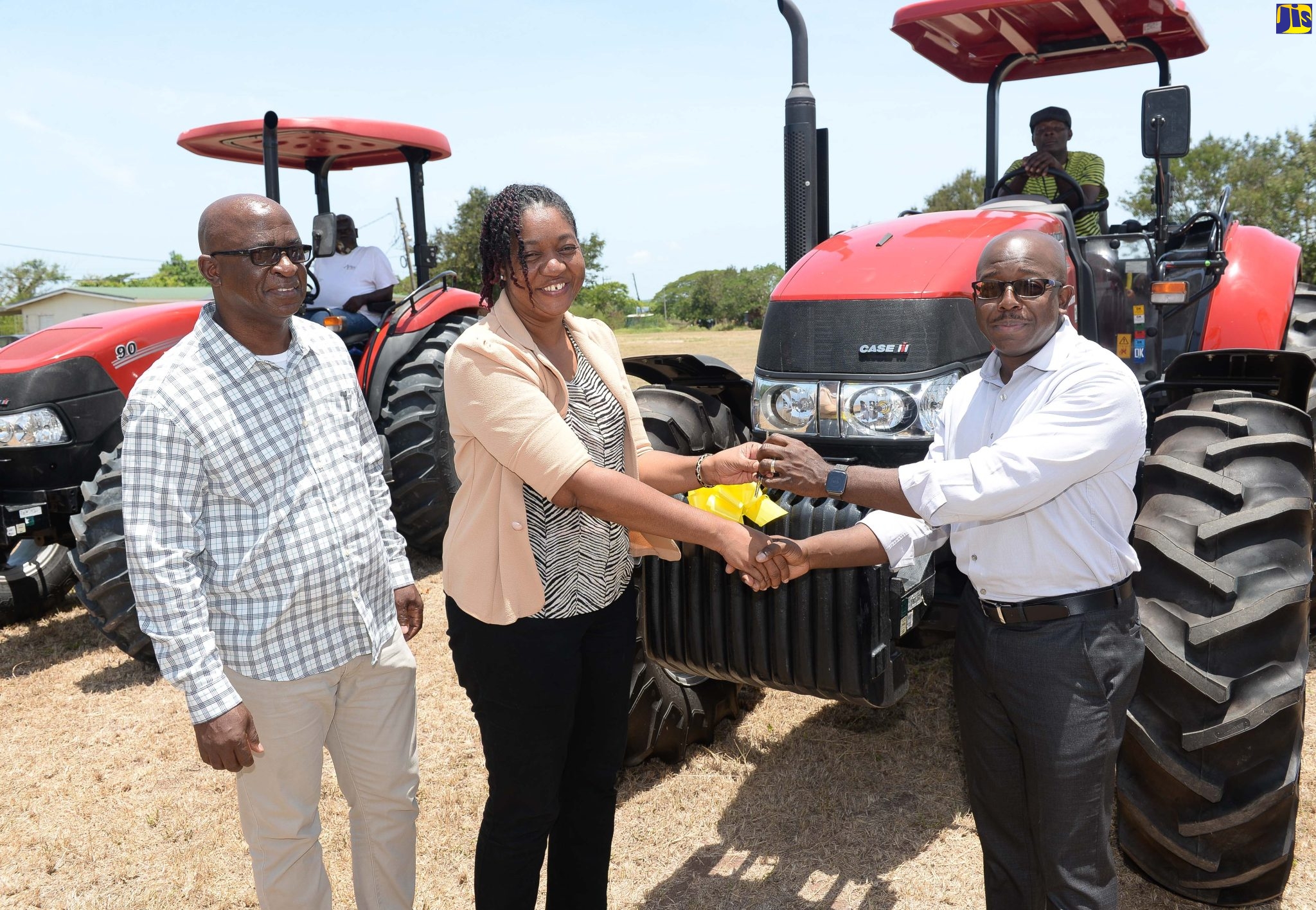Minister of Agriculture and Fisheries, Hon. Pearnel Charles Jr. (right, foreground), presents Deputy Research Director at Bodles Research Station in St. Catherine, Michelle Sherwood, with the keys for the two Case IH Farmall tractors that were handed over to the facility on Friday (June 24). At left is Chief Technical Director in the Agriculture Ministry, Orville Palmer.
