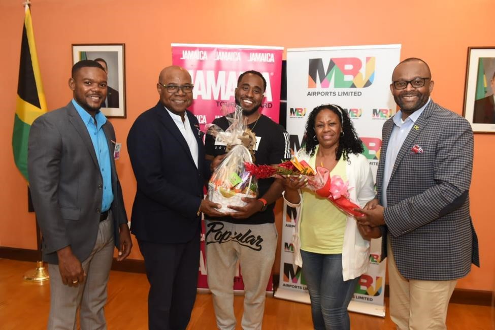 Minister of Tourism,  Hon. Edmund Bartlett (second left), presents a gift basket to California native and Jamaica’s millionth stopover visitor, Brian Simmons (left), on his arrival at the Sangster International Airport in Montego Bay on Wednesday (June 15), on a JetBlue flight from New York.  He was accompanied by his mother, Monica Simmons. Also on hand to welcome Mr. Simmons (from left) are Deputy Mayor of Montego Bay, Richard Vernon; and Director of Tourism, Jamaica Tourist Board (JTB), Donovan White.
