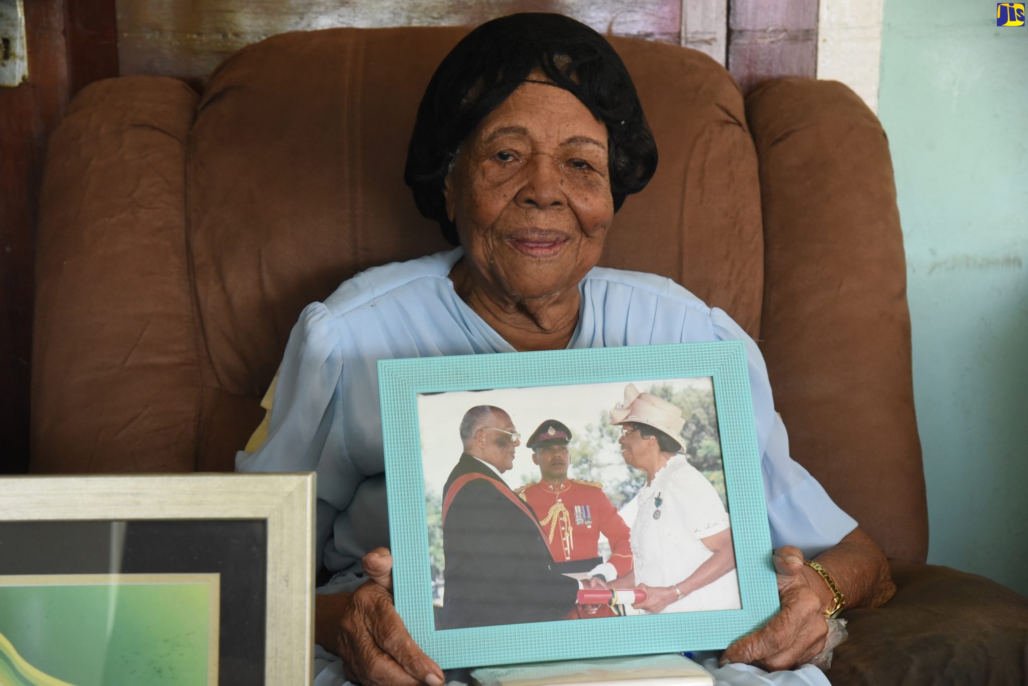 Centenarian Frannie Wright displays a photograph of her being presented with an award by late former Governor General, His Excellency the Most Hon. Howard Cooke, for her contribution to national development. Occasion was a visit to the 102-year-old’s Shalimar Avenue address in Kingston on Friday (July 1) to present her with a gift baskeT as part of the National Council for Senior Citizens (NCSC) post-Centenarians’ Day activities on Friday (July 1).