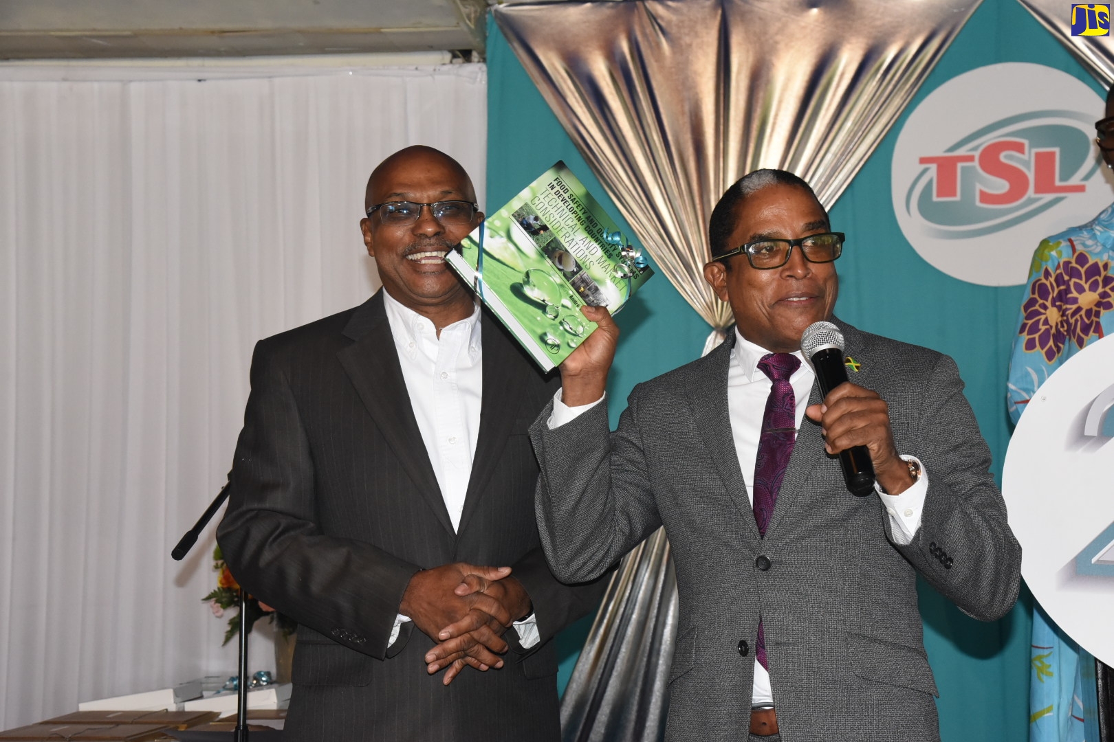 Minister of State in the Ministry of Industry, Investment and Commerce, Dr. the Hon Norman Dunn (right), expressing gratitude to author, Chairman and Chief Executive Officer, Technological Solutions Limited (TSL), Dr. Andre Gordon after being presented with a book entitled 