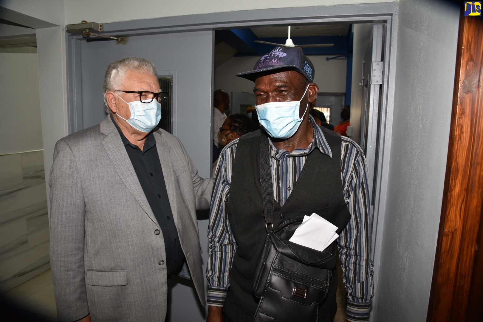 Minister of Labour and Social Security, Hon. Karl Samuda (left), greets veteran farmworker, Clovis Cooper, during a send-off ceremony held at the Ministry’s Overseas Employment Services Centre in downtown Kingston, recently. The workers left the island for Canada.