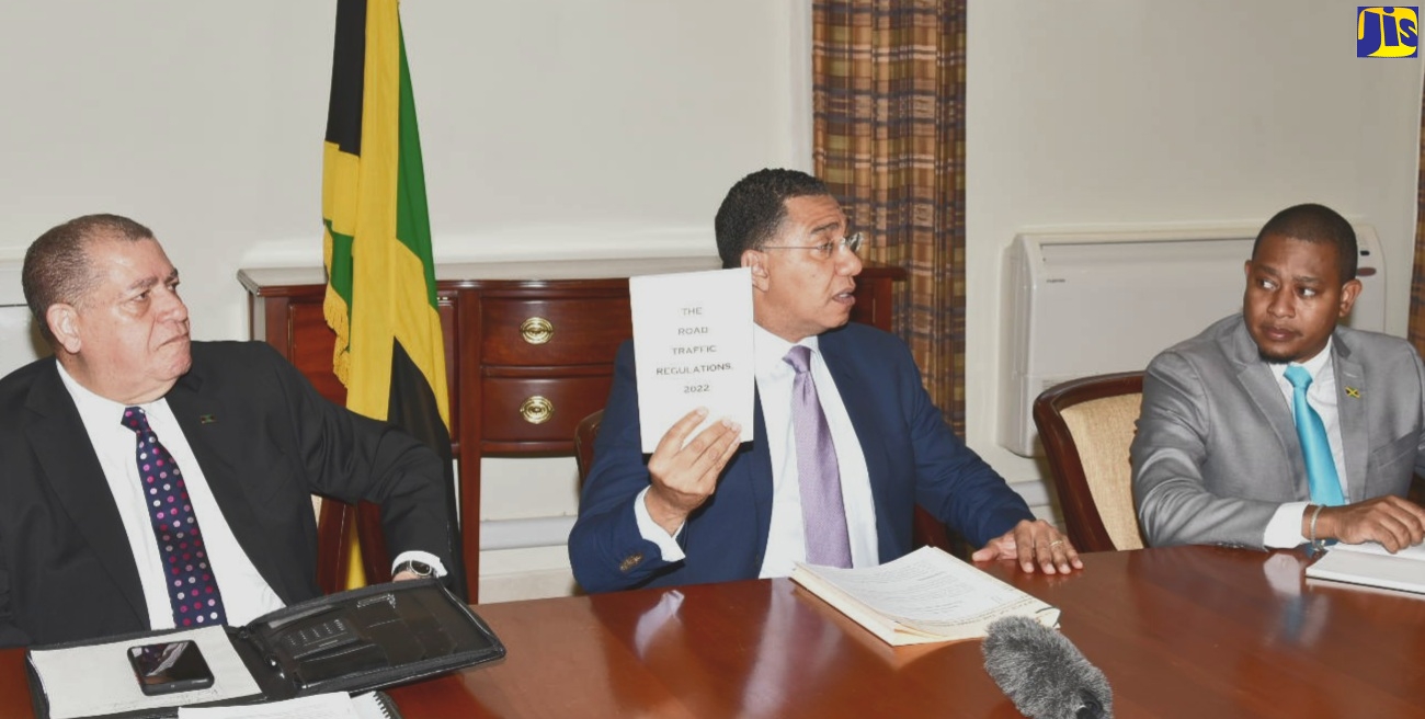 Prime Minister, the Most Hon. Andrew Holness (centre), holds a copy of the new Road Traffic Regulations, 2022 during a meeting of the National Road Safety Council on July 7 at the Office of the Prime Minister. Also present are Minister of Transport and Mining, Hon. Audley Shaw (left) and Minister without Portfolio in the Office of the Prime Minister, Hon. Floyd Green.