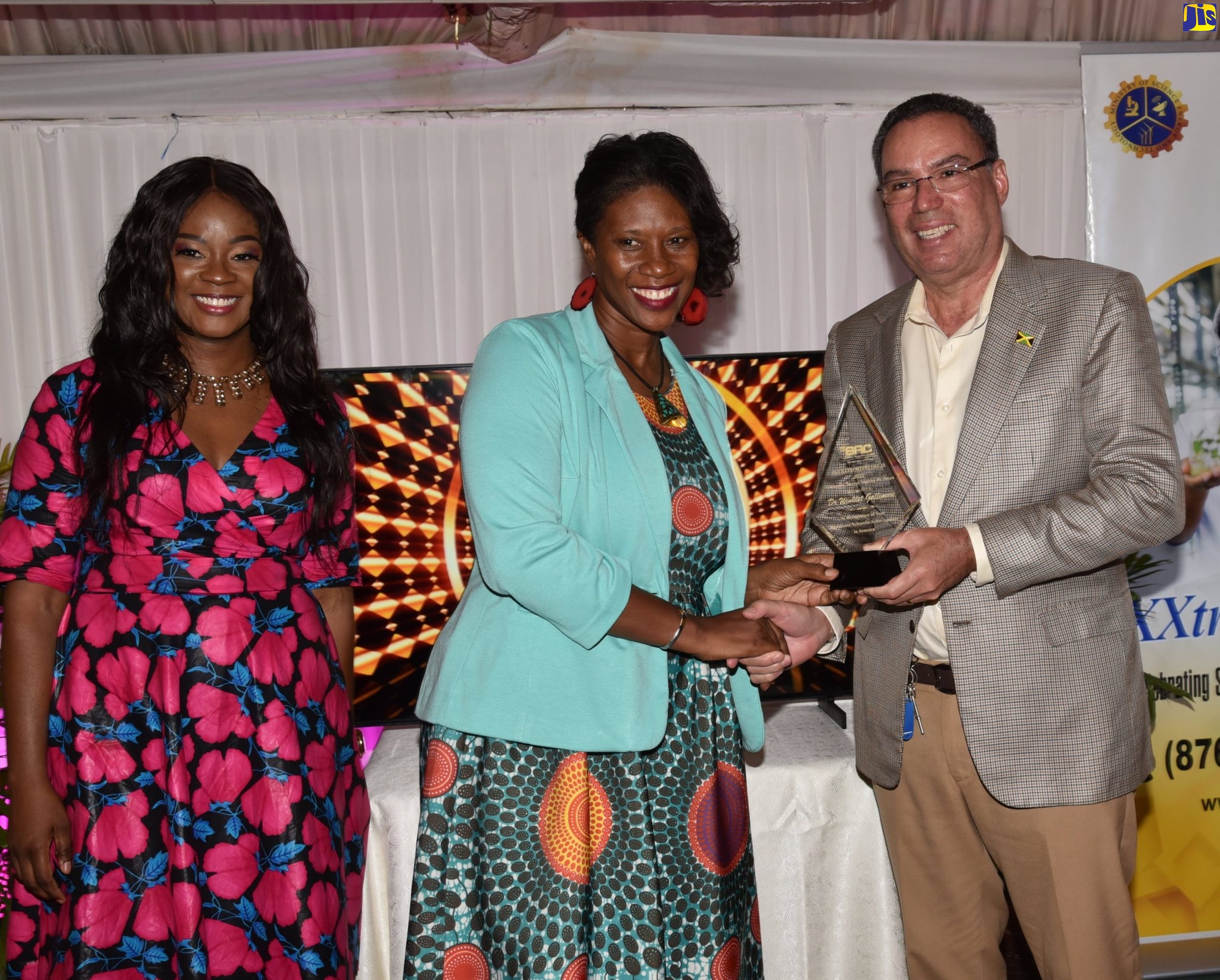Minister of Science, Energy and Technology, Hon. Daryl Vaz (right) presents a plaque to senior lecturer, Department of Chemistry, University of the West Indies, Mona, Dr. Winklet Gallimore (centre), during the official launch of the Scientific Research Council’s (SRC) Science & Technology XXtrordineers JA programme at the Terra Nova All-Suite Hotel in St. Andrew on July 14.  At right is Executive Director, SRC, Dr. Charah T. Watson.