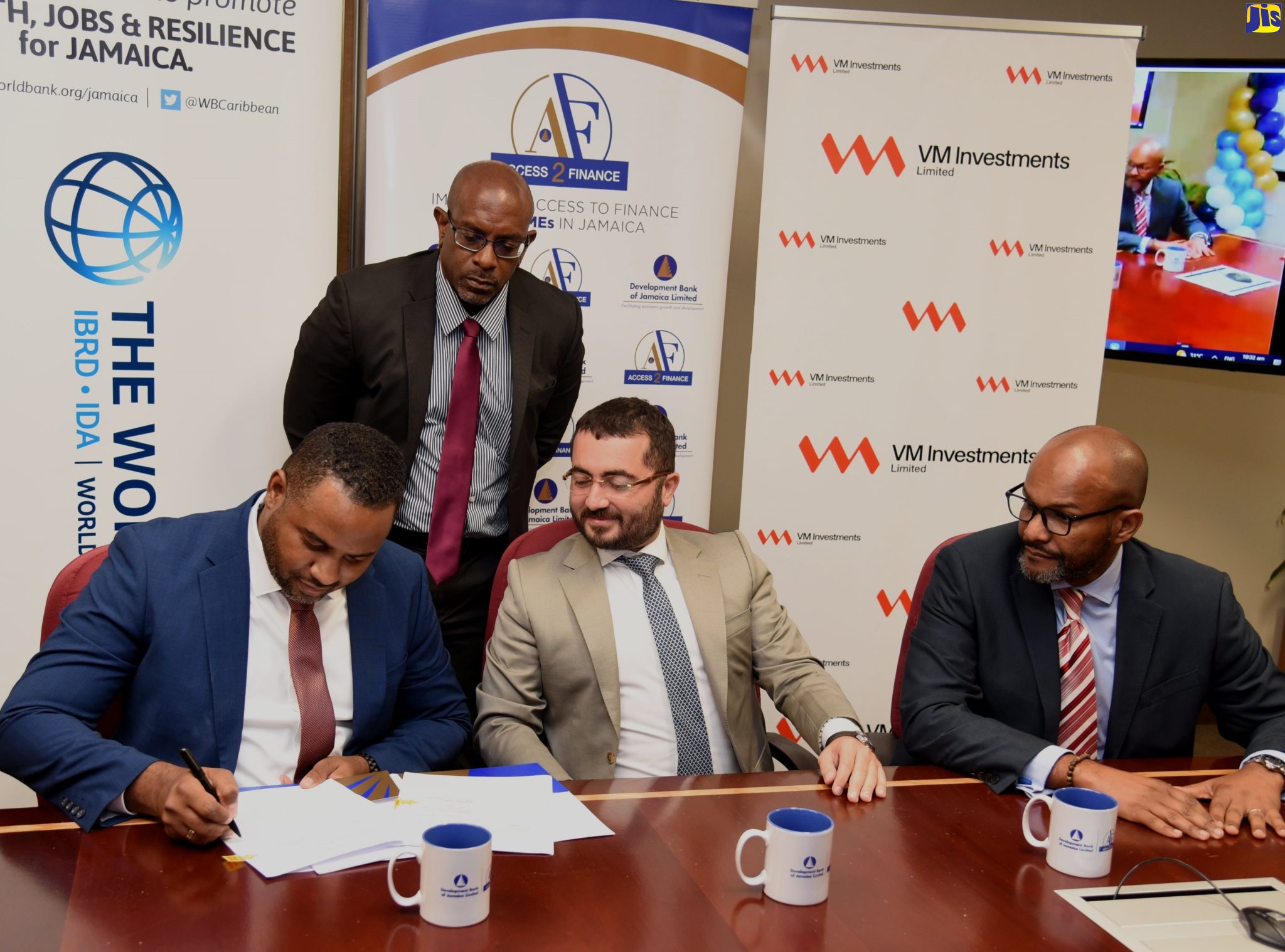 General Manager for the Development Bank of Jamaica (DBJ) Project Management Office, Hugh Grant (left), signs an agreement formalising the DBJ’s partnership with Victoria Mutual Investments Limited (VMIL) for the creation of the Jamaica Actus Small and Medium Enterprise Fund 1 (JASMEF 1). Observing are VMIL Chief Executive Officer and co-signatory, Rezworth Burchenson (right), and Actus Partners Founding Director, Murat Tasci (centre, seated). Overseeing the proceedings is DBJ’s Legal Officer, Adrian Nelson. The signing took place at the DBJ’s head office on Oxford Road in Kingston, on Thursday (June 30).