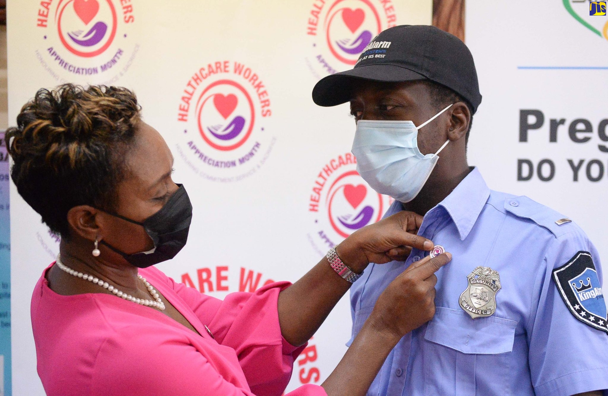 State Minister in the Ministry of Health and Wellness, Hon. Juliet Cuthbert-Flynn (left), places the Healthcare Workers Appreciation Month pin on the lapel of security officer at the Victoria Jubilee Hospital (VJH), Adrian Wright, during a pinning ceremony held at the facility in downtown Kingston on Wednesday (July 13). The event, which recognised staff of the VJH and Kingston Public Hospital (KPH), was held in observance of Healthcare Workers Appreciation Day.