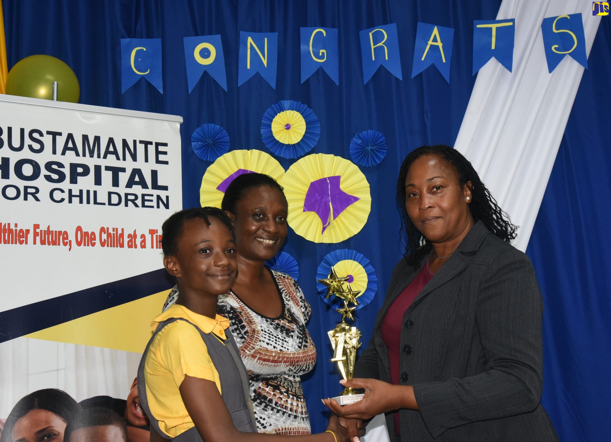 Winner in the Bustamante Hospital for Children poster competition, Shamara Chin (left), is presented with her trophy by Administrator at the hospital, Karlene Taylor-McKenzie (right), while mother of the student, Nina Brown (centre), shares in the occasion. The ceremony was at the hospital in St. Andrew on June 30.