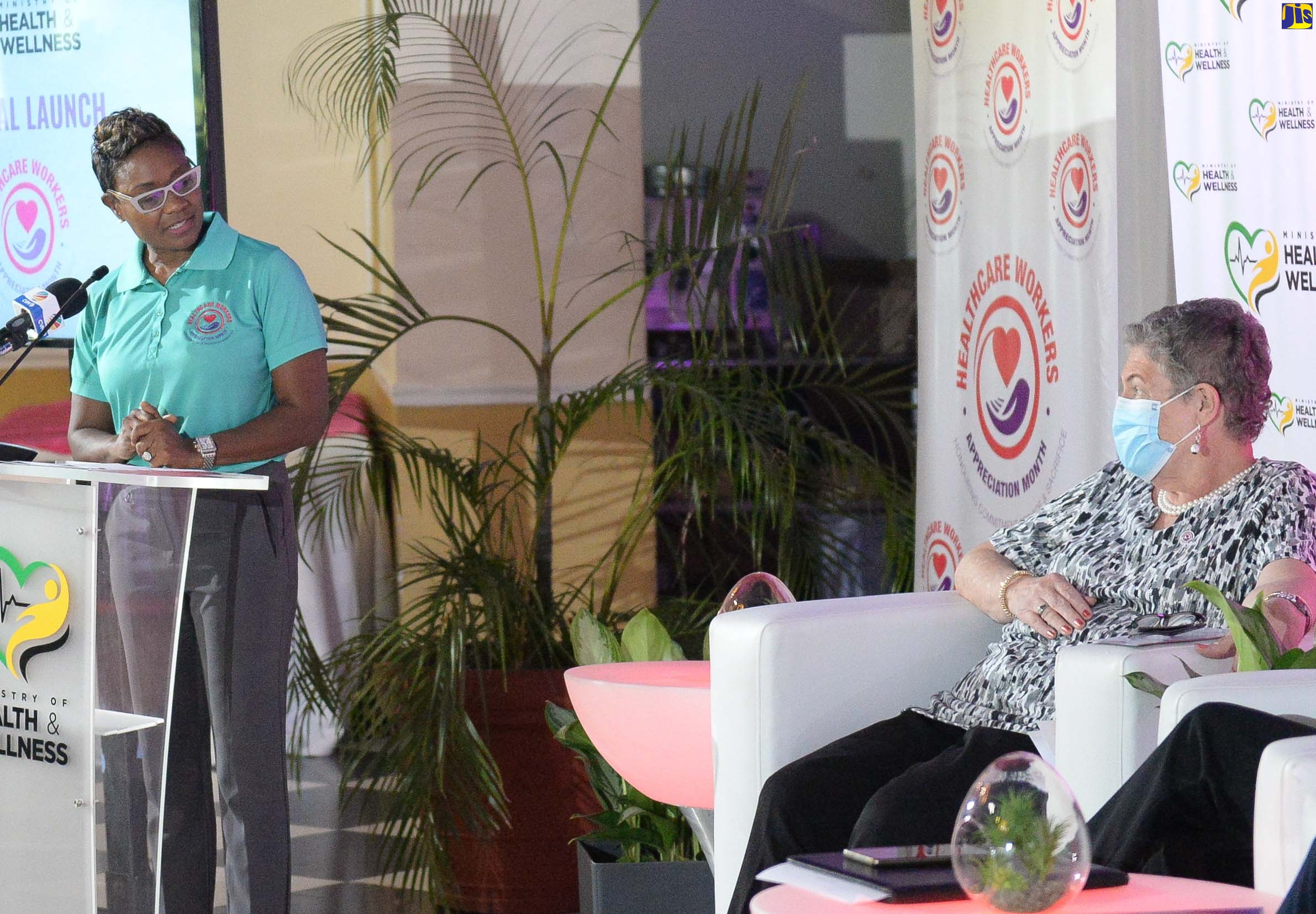 Minister of State in the Ministry of Health and Wellness, Hon. Juliet Cuthbert-Flynn (left), makes a comment to Professor the Most Hon. Dr. Denise Eldemire Shearer, as she addresses the official launch of Healthcare Workers Appreciation Month on Monday (July 4), at the Terra Nova All-Suite Hotel in St. Andrew. Professor Shearer is  Chairperson for the Healthcare Workers Appreciation Committee.
