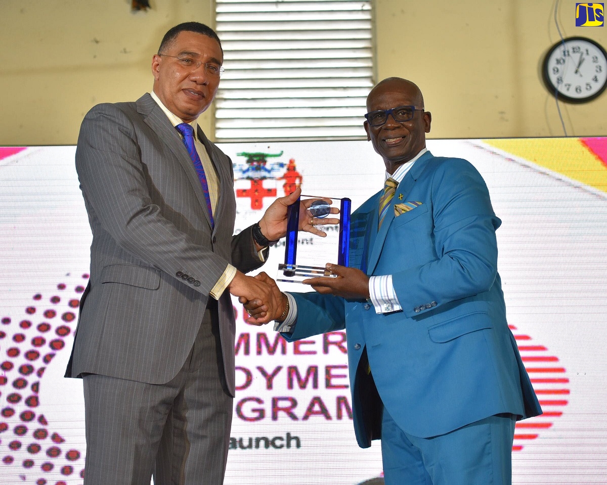Prime Minister, the Most Hon. Andrew Holness (left), accepts an award from Minister of Local Government and Rural Development, Hon. Desmond McKenzie, during the launch of the Youth Summer Employment Programme (YSEP) at the Mannings School in Savanna-la-Mar, Westmoreland on Friday (July 15).