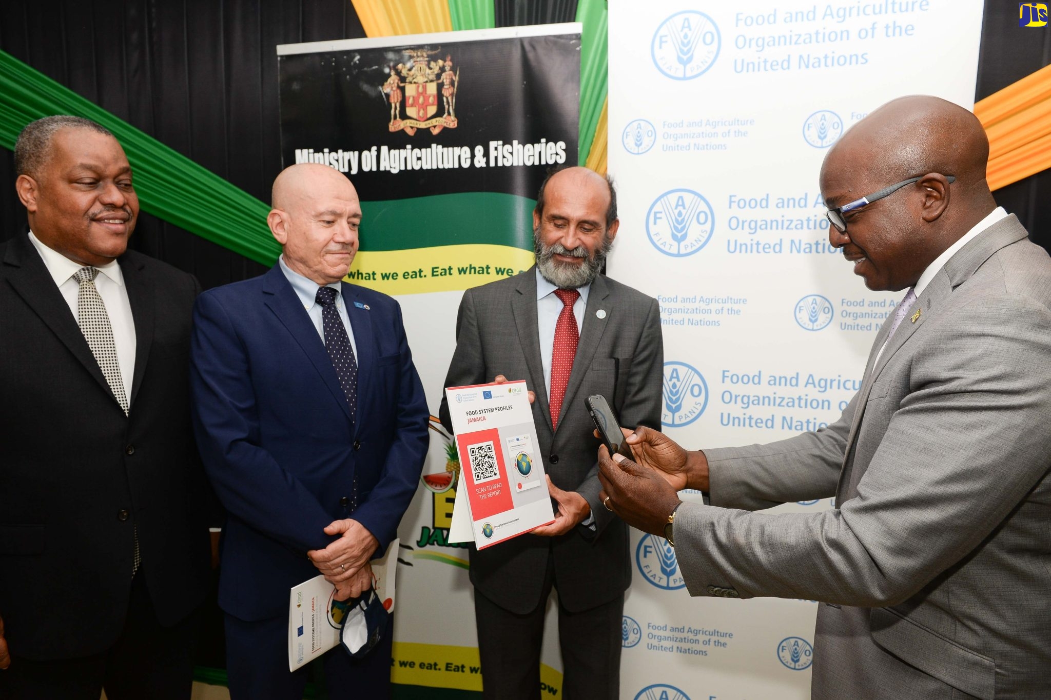 Minister of Agriculture and Fisheries, Hon. Pearnel Charles Jr. (right), uses his cellphone to scan and access the ‘Jamaica Food Systems Profile’ at the handover of the document by the Food and Agriculture Organization (FAO) on Tuesday (July 5), at the Ministry’s offices in Kingston. Looking on (from left) are United Nations Resident Coordinator, Dr. Garry Conille; Head of Cooperation, Delegation of the European Union to Jamaica, Aniceto Rodriguez Ruiz; and FAO Representative for Jamaica, The Bahamas and Belize, Dr Crispim Moreira.