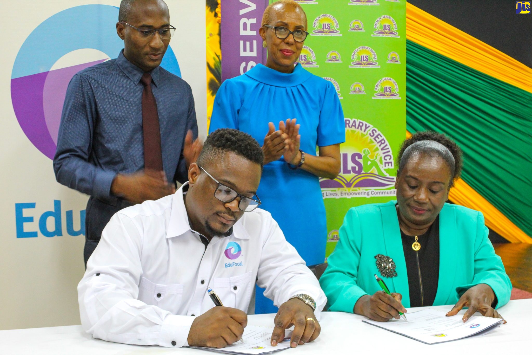 Chief Executive Officer (CEO), EduFocal Limited, Gordon Swaby (left, seated) and Director-General, Jamaica Library Service (JLS), Maureen Thompson (right, seated) sign the partnership agreement between the entities for the establishment of learning centres across the JLS network. Observing the proceedings are Education and Youth Minister, Hon. Fayval Williams (right, standing) and JLS Board Director, Dimitri South. The ceremony was held on Thursday (August 11) at the Kingston and St. Andrew Parish Library. The JLS is comprised of 111 libraries, 334 mobile library stops, and 898 school libraries across 13 parishes.