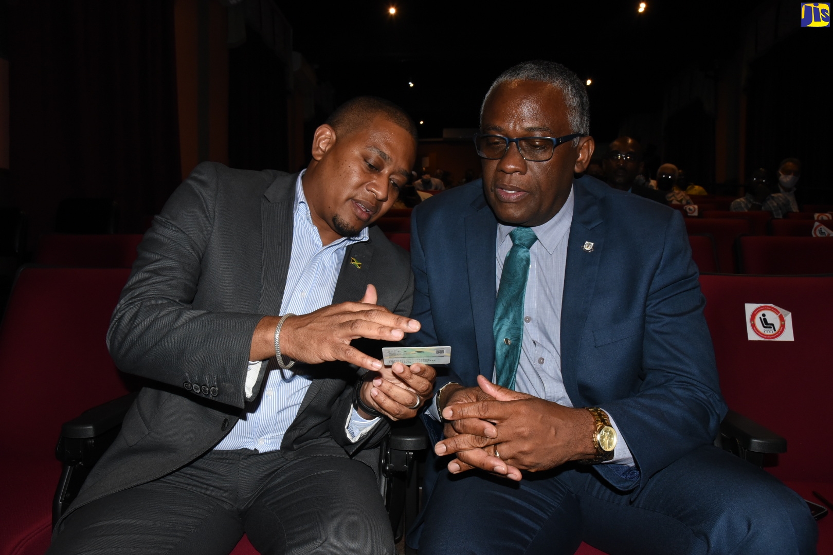 Hon. Floyd Green (left), Minister without Portfolio in the Office of the Prime Minister with Responsibility for the National Identification System (NIDS), shows a sample card to Custos Rotulorum for the parish of Manchester, Hon. Garfield Green, following the Minister