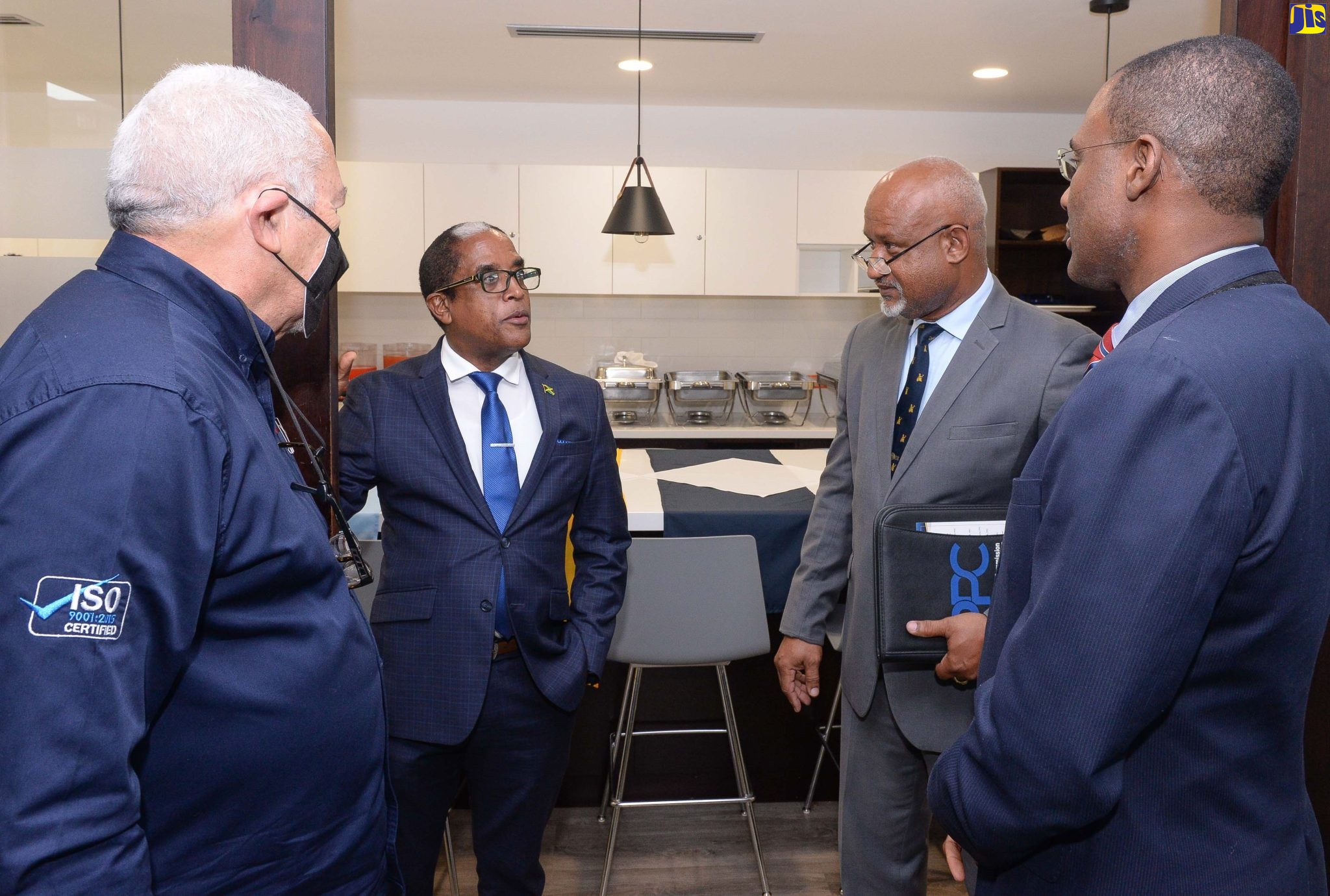 Minister of Finance and the Public Service, Dr. the Hon. Nigel Clarke (right), listens to State Minister in the Ministry of Industry, Investment and Commerce, Dr. the Hon. Norman Dunn (second left), at a ceremony,  held at the Public Procurement Commission (PPC), in Kingston, on August 24, to celebrate the entity’s ISO 9001:2015 certification achievement.  Also listening (from left) are Chairman of the PPC, Raymond McIntyre, and PPC’s Executive Director, Lieutenant Commander (Ret’d) Paul Wright.