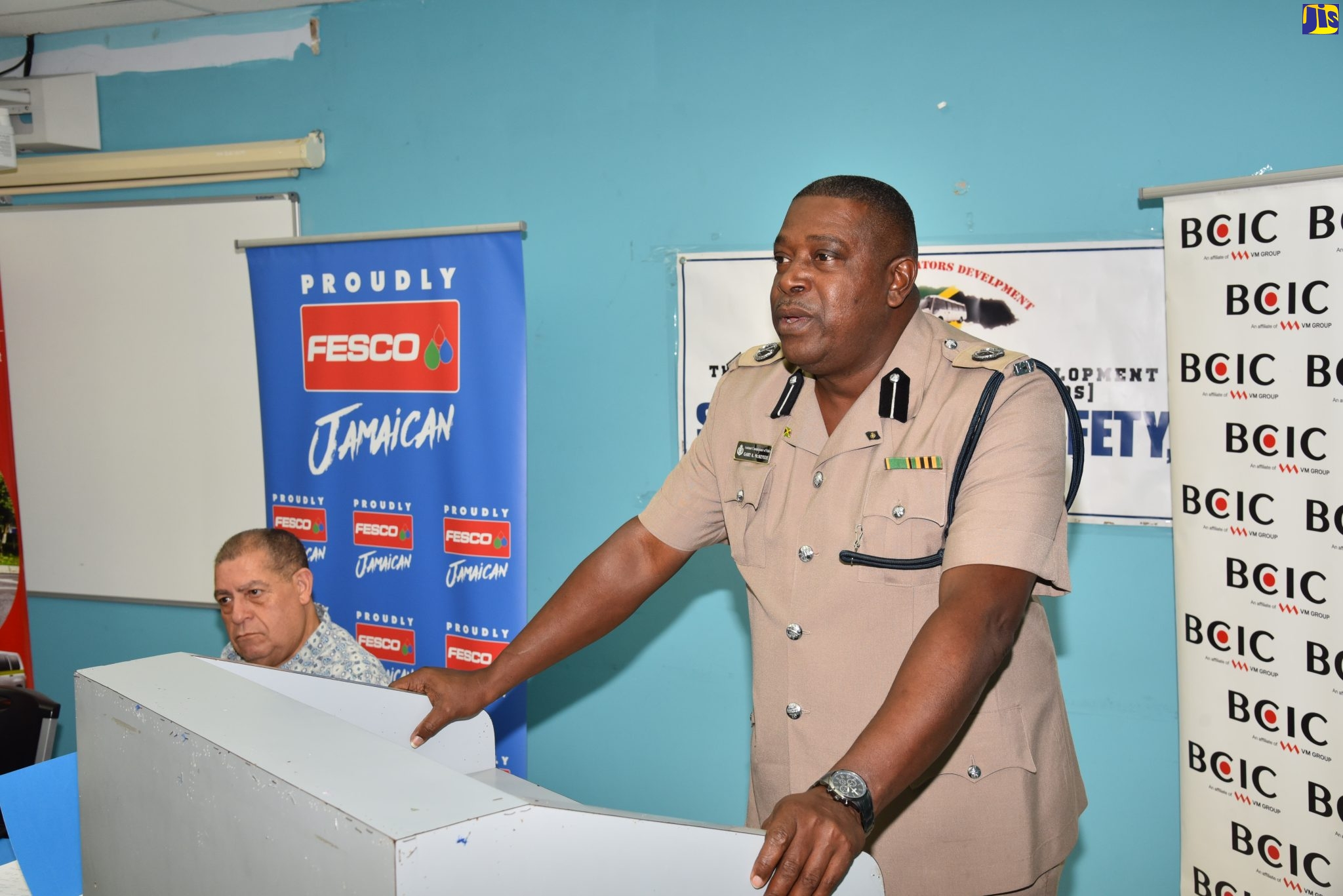 Head of the Public Safety and Traffic Enforcement Branch (PSTEB) of the Jamaica Constabulary Force, Assistant Commissioner of Police, Gary McKenzie, addresses the recent presentation ceremony for the Blue Ribbon First Responders Training Programme at the University of Technology, Jamaica. Listening keenly is Minister of Transport and Mining, Hon. Audley Shaw.