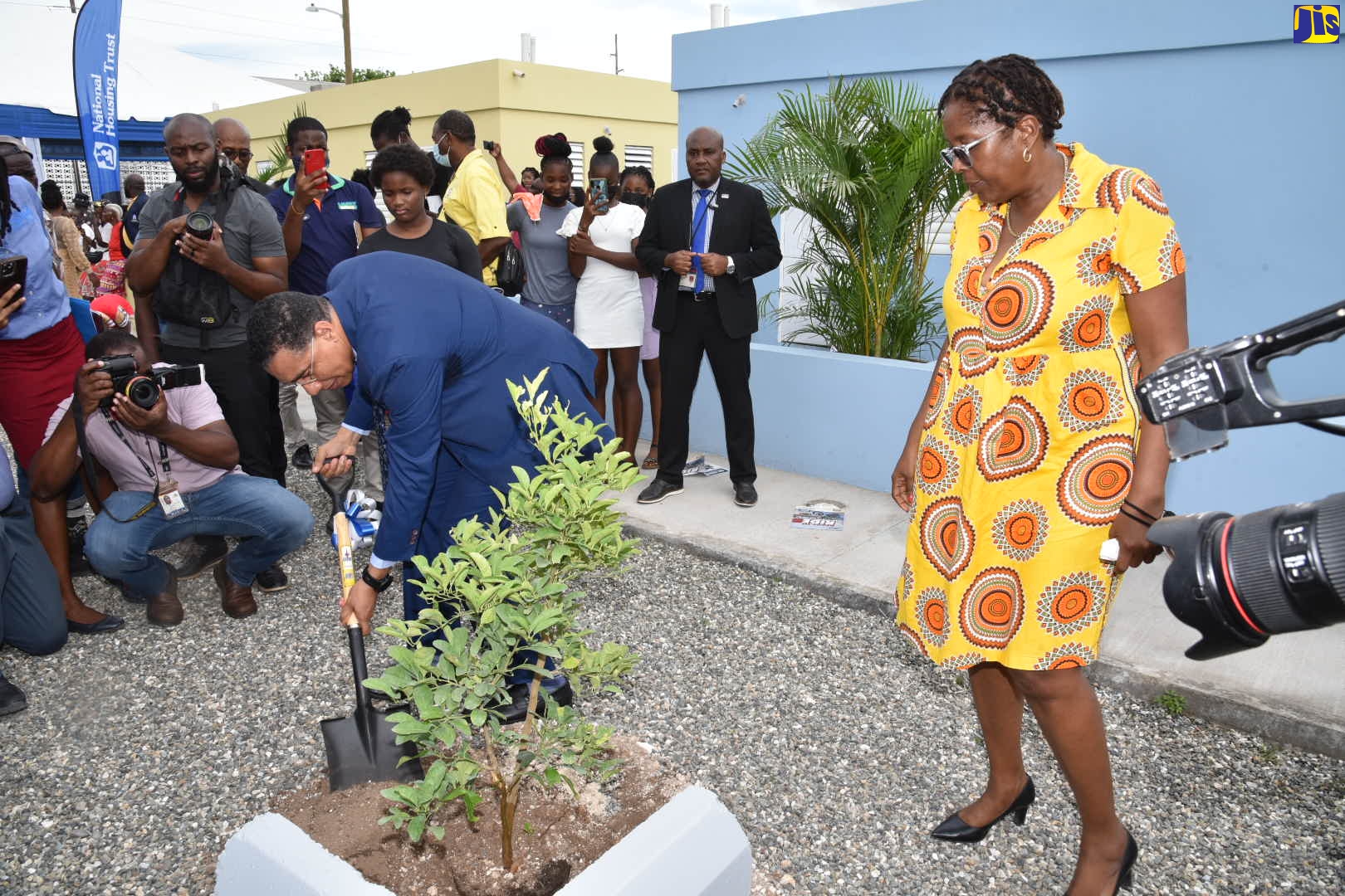 Prime Minister, the Most Hon. Andrew Holness, plants a tree on the site of the recently completed Majesty Gardens phase 1A housing development in St. Andrew. Among those looking on is Member of Parliament for St. Andrew South Western, where the development is located, Dr. Angela Brown-Burke (right).

Prime Minister Holness handed over the keys to the proud new homeowners during a ceremony on August 24. The development, comprising 32 duplex units, was spearheaded by the National Housing Trust (NHT).