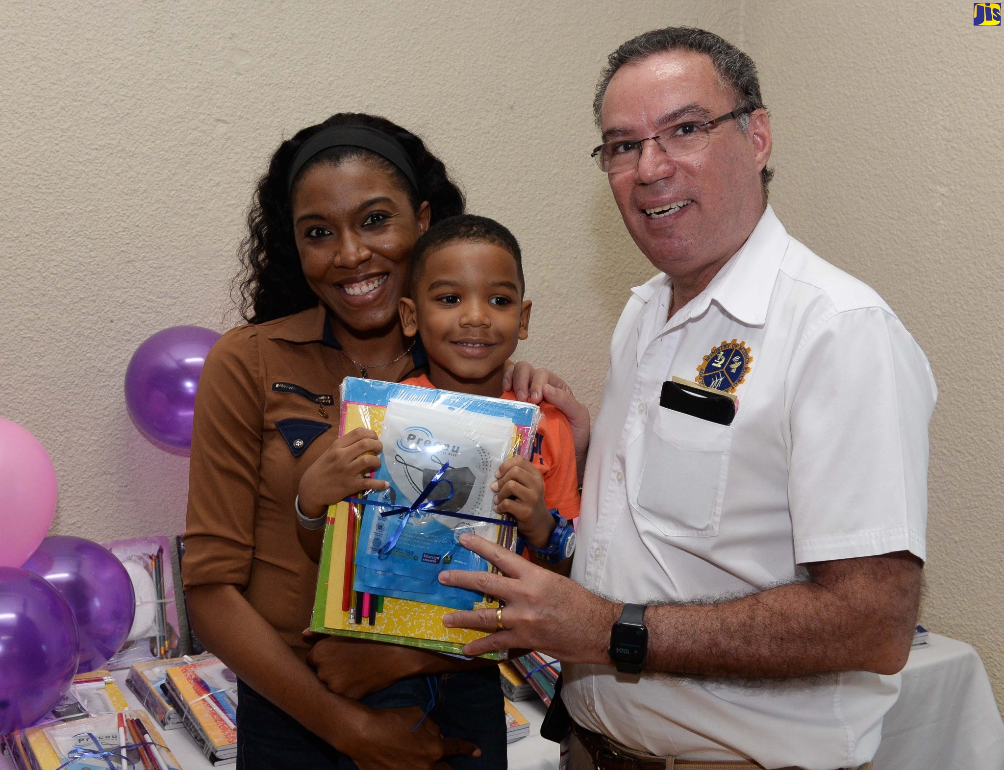 Minister of Science, Energy and Technology, Hon. Daryl Vaz (right), presents a back-to-school package to young Asier Bryan, who is being held by his mother Treviece Gayle. The occasion was a back-to-school fair hosted by staff of the Ministry on August 18 at the PCJ Building, Kingston. It catered to children of members of employees of the Ministry and their relatives.