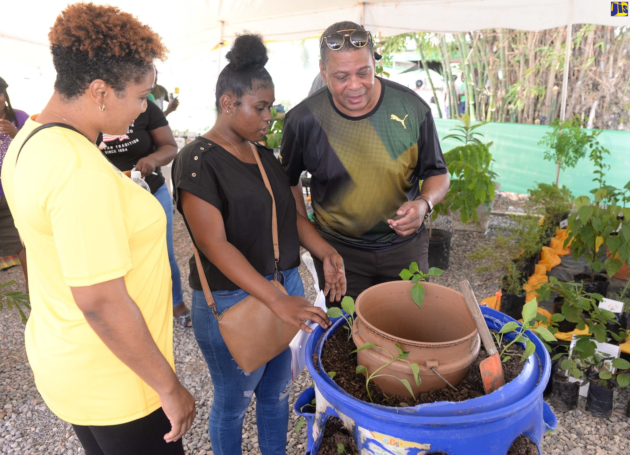 Angelique Chen of St Mary (centre) shows off her vertical drum planter to patron, Tamica Afflick (left) and Dean of the Consular Corps of Jamaica, Robert Scott (right) at the Denbigh Agricultural, Industrial and Food Show in Clarendon on Saturday (July 30).