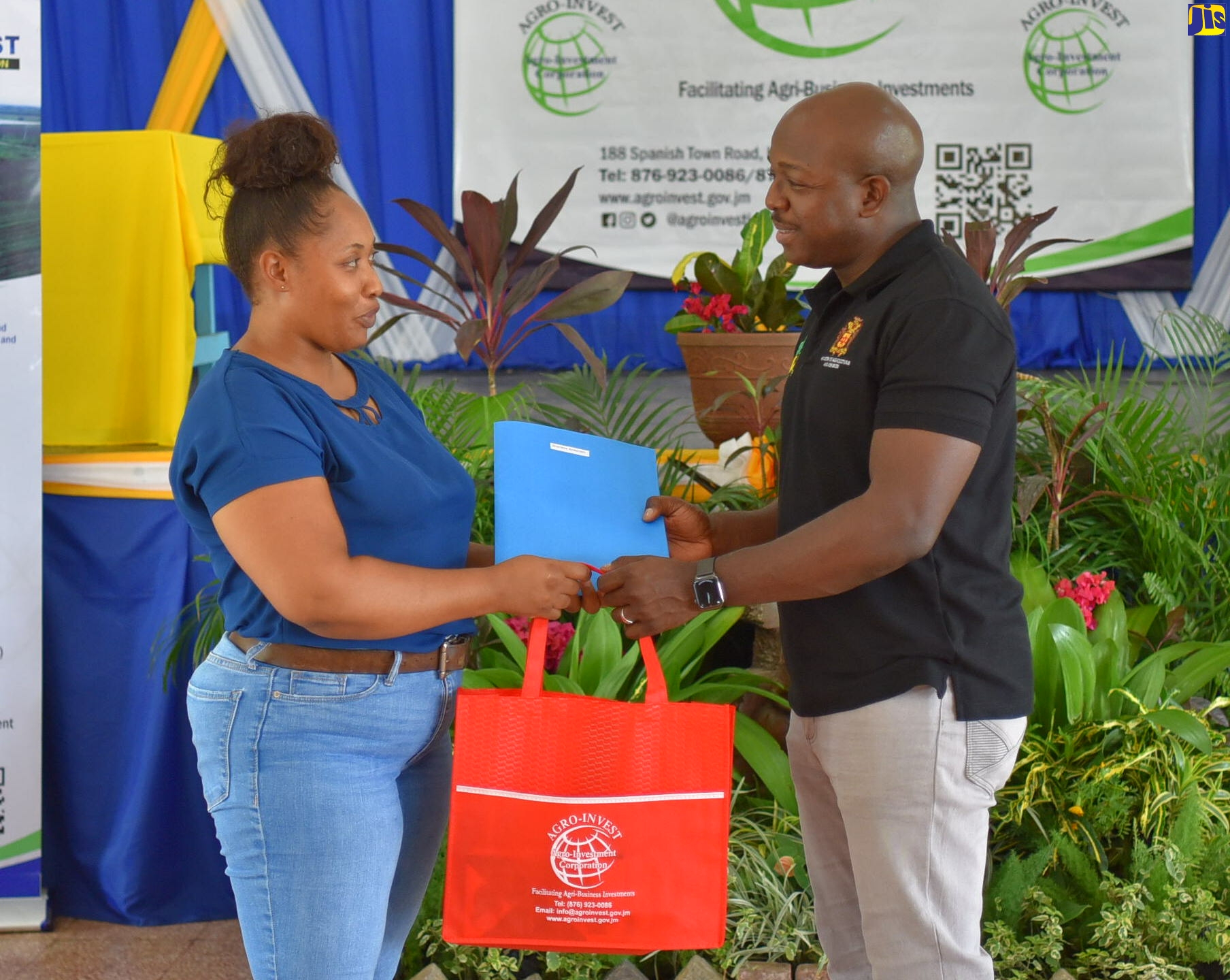 Minister of Agriculture and Fisheries, Hon. Pearnel Charles Jr. (right), presents Sharlene Anderson with a lease agreement for agricultural lands, during a ceremony  at the Ebony Park HEART Academy in Clarendon, on August 9.