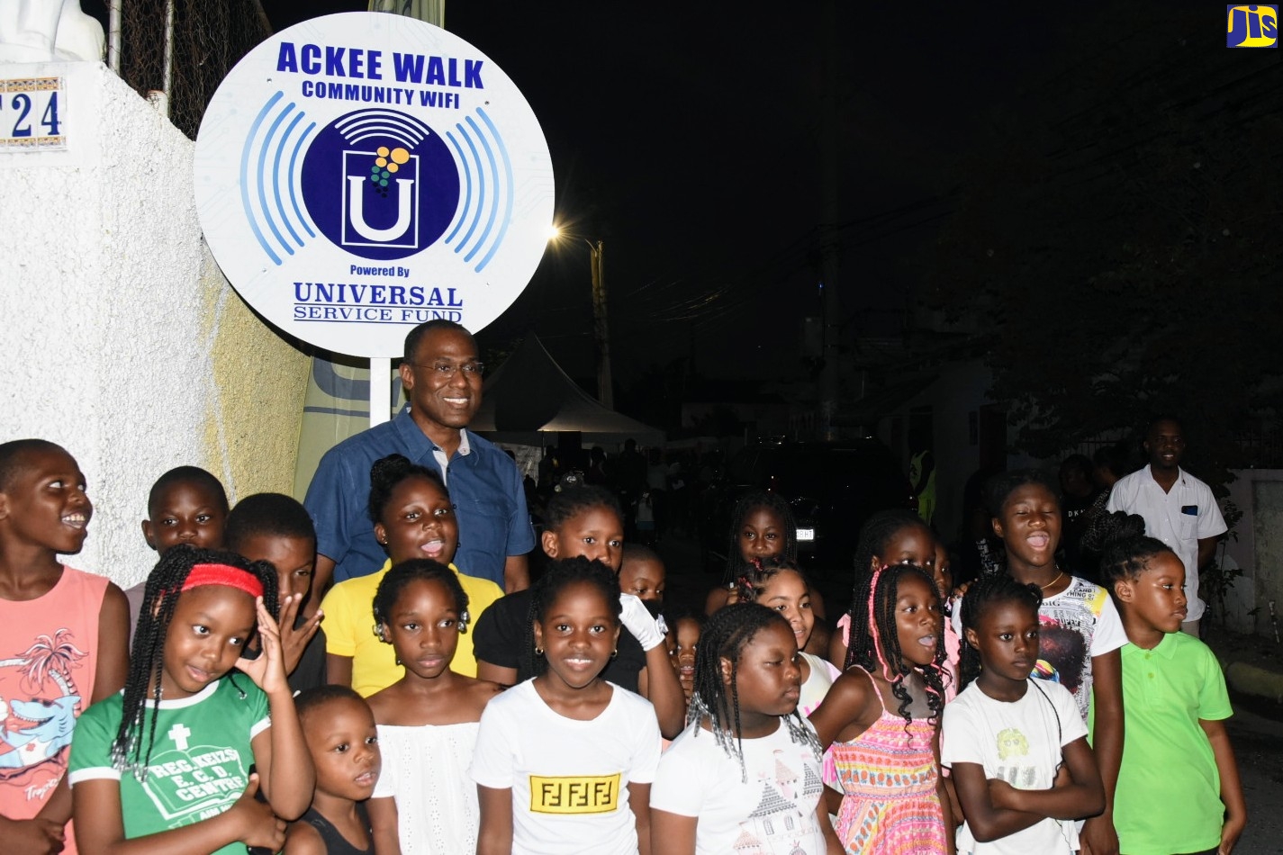 Minister of Finance and Public Service and Member of Parliament for St. Andrew North Western, Dr. the Hon. Nigel Clarke, pauses for a photo with children of the Ackee Walk community, during the launch of a free secured Wi-Fi hotspot in the area on Monday (August 15).