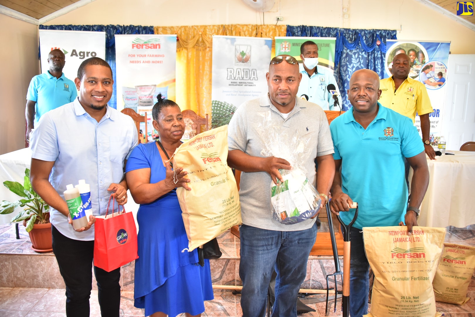 Minister of Agriculture and Fisheries, Hon. Pearnel Charles Jr.(right), and Minister Without Portfolio in the Office of the Prime Minister, Hon. Floyd Green (left), who is Member of Parliament for St. Elizabeth South West, hand over fertiliser and other farming supplies to farmers, Zenora Davis (second from left) and Peter Campbell, during a presentation of agricultural supplies to fire-affected farmers at the New Testament Church of God in Flagaman, St. Elizabeth, on September 22.