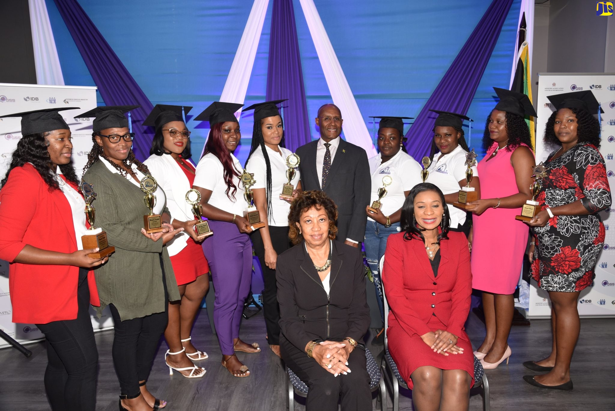 Minister of Industry, Investment and Commerce, Senator the Hon. Aubyn Hill (fifth right, standing); HEART/NSTA Trust Managing Director, Dr. Taneisha Ingleton (right, seated); and Jamaica Promotions Corporation (JAMPRO) President, Diane Edwards (left, seated), are flanked by graduates of the Global Services Sector (GSS) Apprenticeship Programme during the inaugural graduation ceremony at JAMPRO’s head office in Kingston, on Wednesday (September 14).
