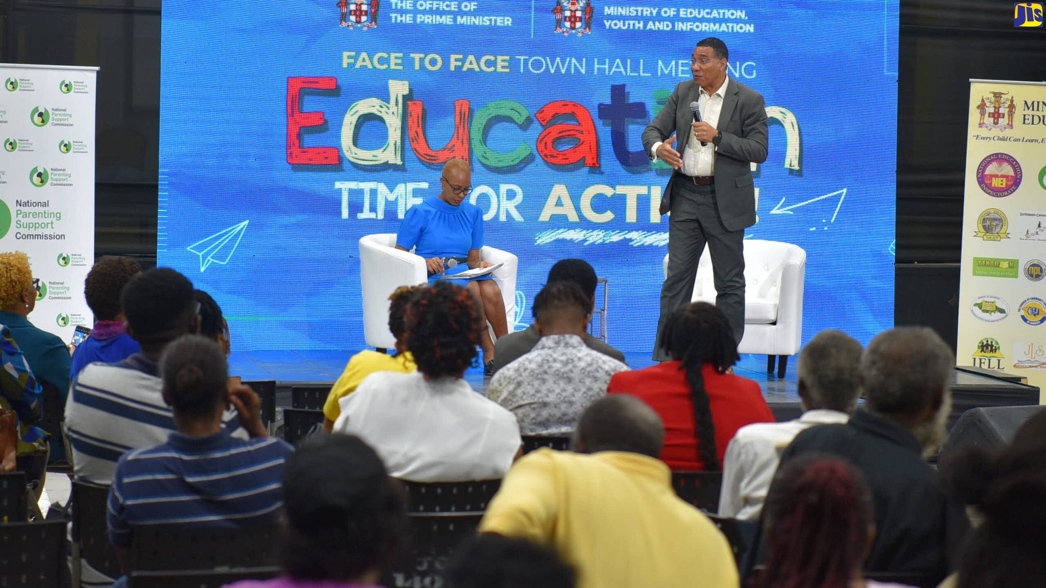 Prime Minister, the Most Hon. Andrew Holness (standing), addresses a townhall meeting at Jamaica College, in St. Andrew, on Friday (September 9). Seated is Education and Youth Minister, Hon. Fayval Williams. The meeting was organised by the Office of the Prime Minister (OPM).