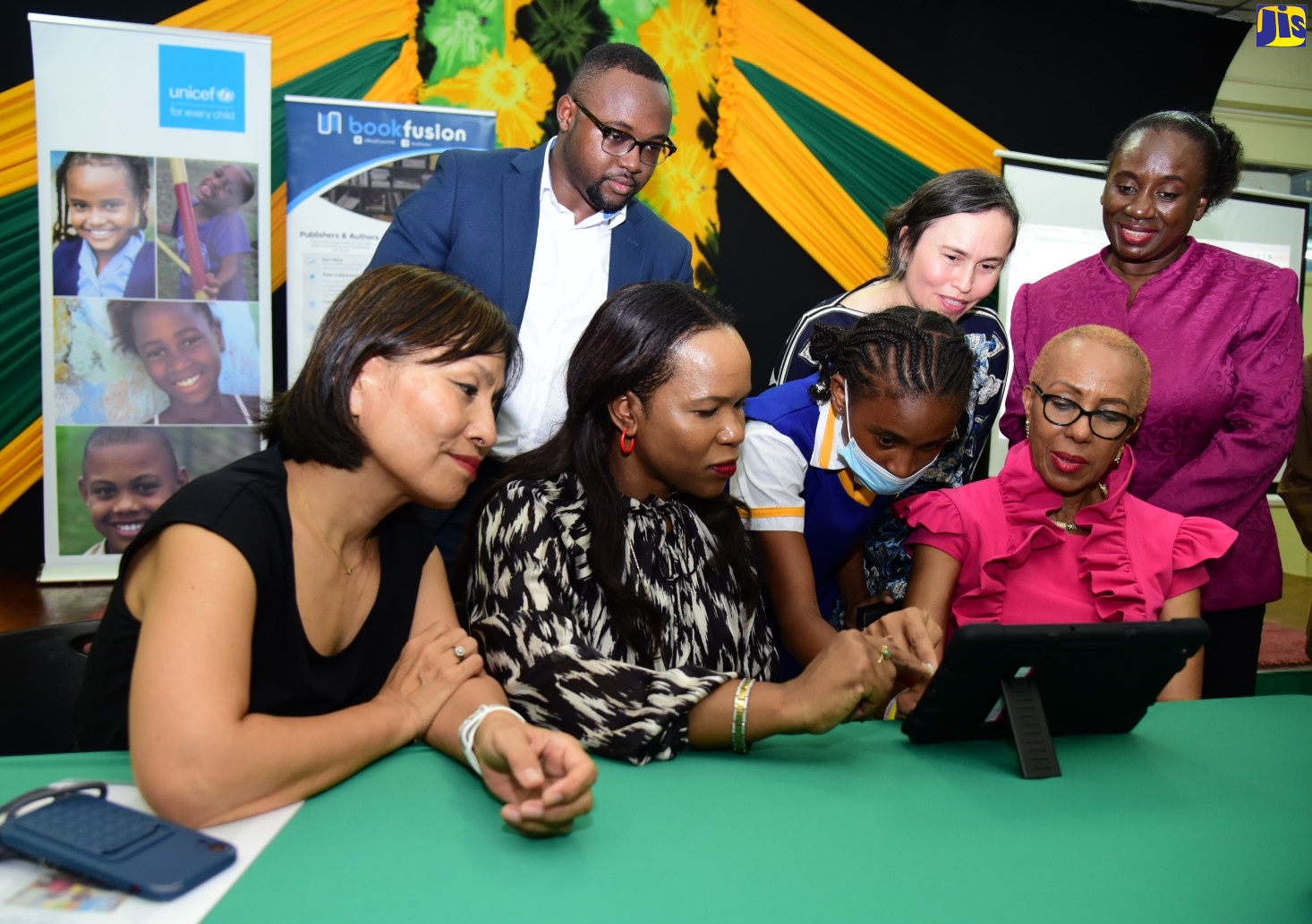 Minister of Education and Youth, Hon. Fayval Williams (seated, right) along with (seated from left) United Nations Children’s Fund (UNICEF) Jamaica Country Representative, Mariko Kagoshima; Acting Chief Education Officer in the Ministry of Education and Youth, Dr. Kasan Troupe and grade-seven student at St. Hugh’s High School, Shakacia Greenland, view a digital textbook, at the recent launch of the Accessible Digital Textbook Prototype in Jamaica at the Joyce Robinson Hall, Kingston and St. Andrew Parish Library. Others (standing from left) are Founder and Chief Executive Officer, BookFusion, Dwayne Campbell; Regional Inclusive Education and Disability Specialist, UNICEF, Cynthia Brizuela and Director General, Jamaica Library Service, Maureen Thompson.