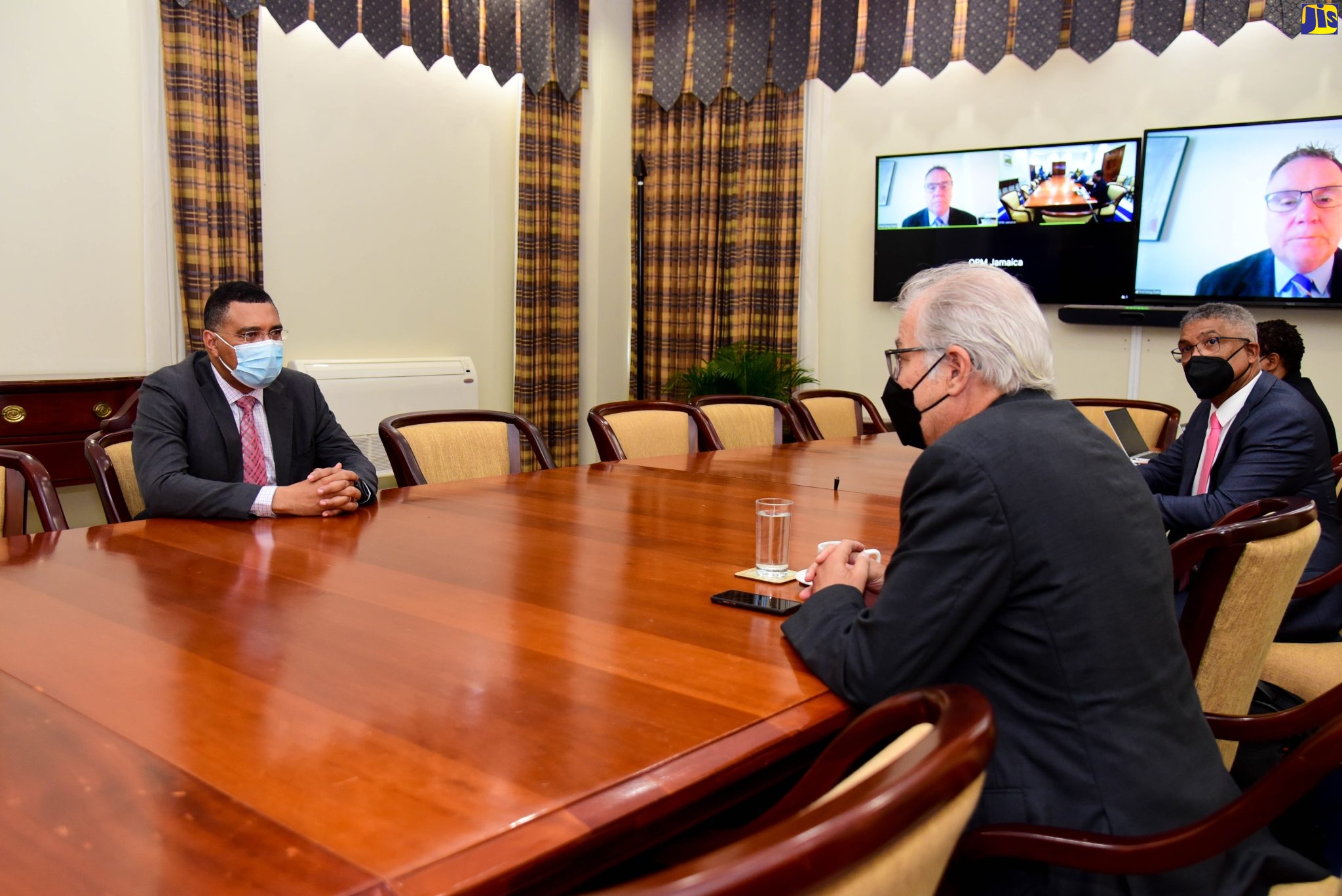 Prime Minister, the Most Hon. Andrew Holness (left), speaking with Chairman of PanJam Investment Limited, Stephen B. Facey (right) and Chairman, Board of Directors, Victoria Mutual Building Society (VMBS), Michael McMorris, during a courtesy call at the Office of the Prime Minister in St. Andrew on October 12. Joining the meeting remotely is international urban development expert, Professor Greg Clark.