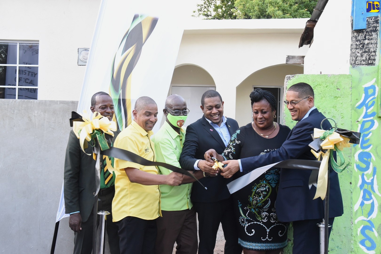 Minister without Portfolio in the Office of the Prime Minister, Hon. Floyd Green (fourth left), cuts the ribbon to the brand-new home of beneficiary Julia Rogers (second right), at the handover of two houses constructed under the New Social Housing Programme (NSHP), on Thursday (October 6), in Central Kingston. Sharing in the moment are (from left) community member, Orlando Williams; Mayor of Kingston, Senator Councillor Delroy Williams; Local Government and Rural Development Minister, Hon. Desmond McKenzie; and Member of Parliament for the area,  Donovan Williams.