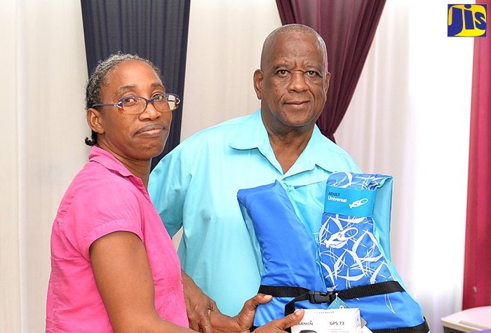 Minister of State in the Ministry of Agriculture and Fisheries, Hon. Franklin Witter (right), presents fisher Teena Trought with safety gear and a global positioning system (GPS) device, during the graduation ceremony for a safety-at-sea training programme at the Caribbean Maritime University (CMU) on Thursday (September 29).