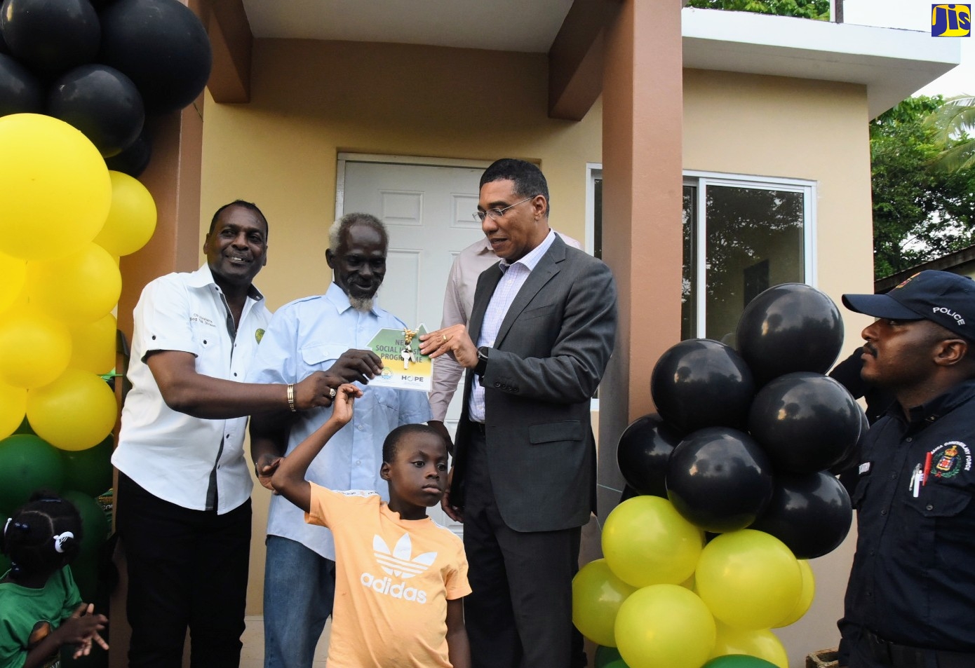 Prime Minister, the Most Hon. Andrew Holness (right), hands over the keys for a new house to resident of Shenton,  Bog Walk, in St. Catherine,  Francis Dixon (centre), on October 12. At left is  Councillor for the Bog Walk Division, Peter Abrahams, and at front is Oswald, son of Mr. Dixon. The unit was constructed under the Government’s New Social Housing Programme (NSHP).
