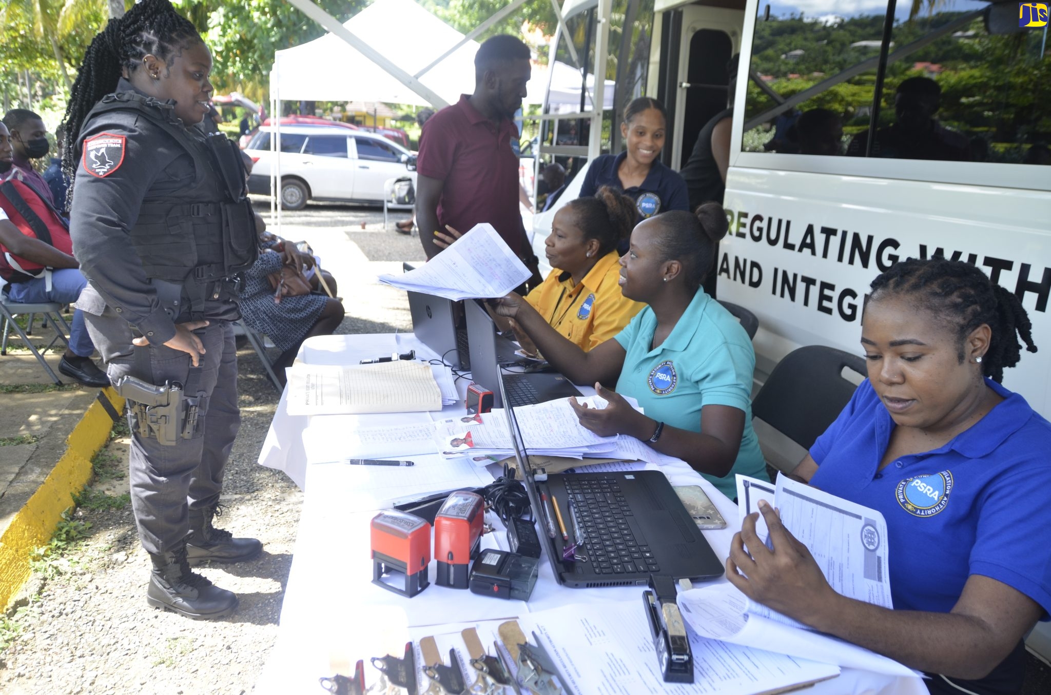 Staff of the Private Security Regulation Authority (PSRA) (at right) respond to queries from Jadieve Robinson from Hawkeye security, during the agency’s mobile registration unit stop at Turtle River Park in Ocho Rios, St. Ann, on Wednesday ( October 12). 

