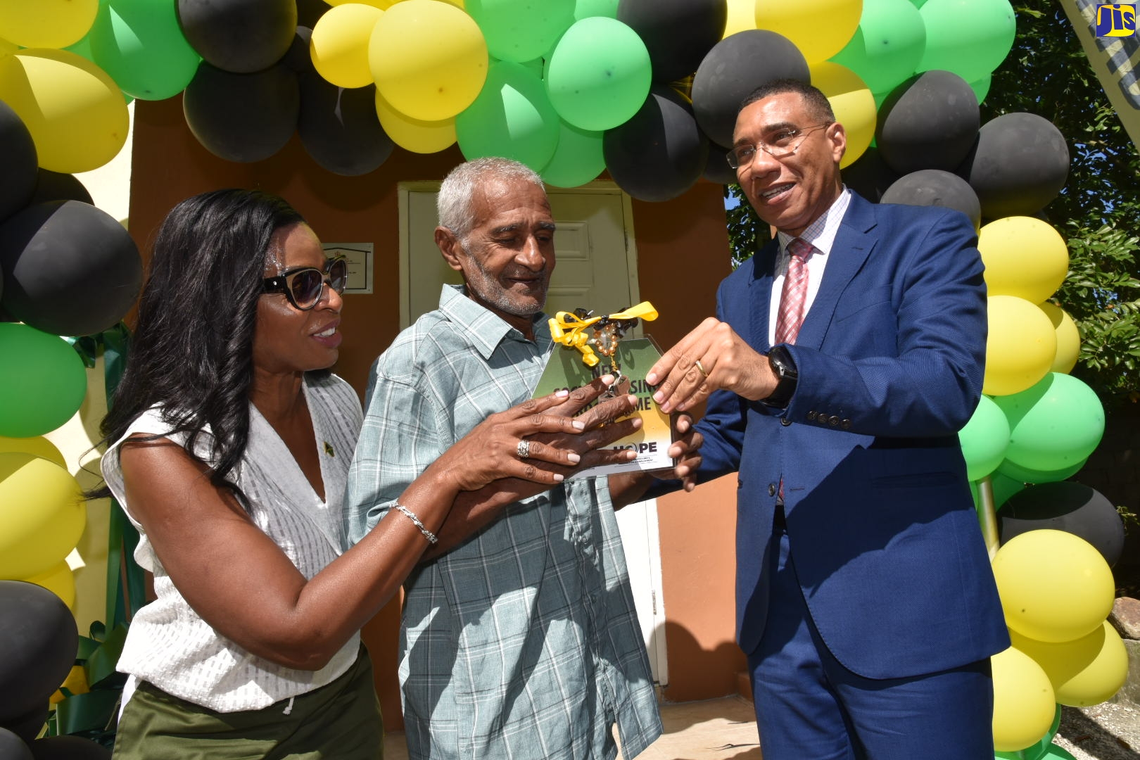 Prime Minister, the Most Hon. Andrew Holness (right), presents the keys to a social housing unit to Duckenfield resident, Keith James, in St. Thomas Eastern, on Wednesday (October 26). At left is Member of Parliament for the constituency, Dr. Michelle Charles.