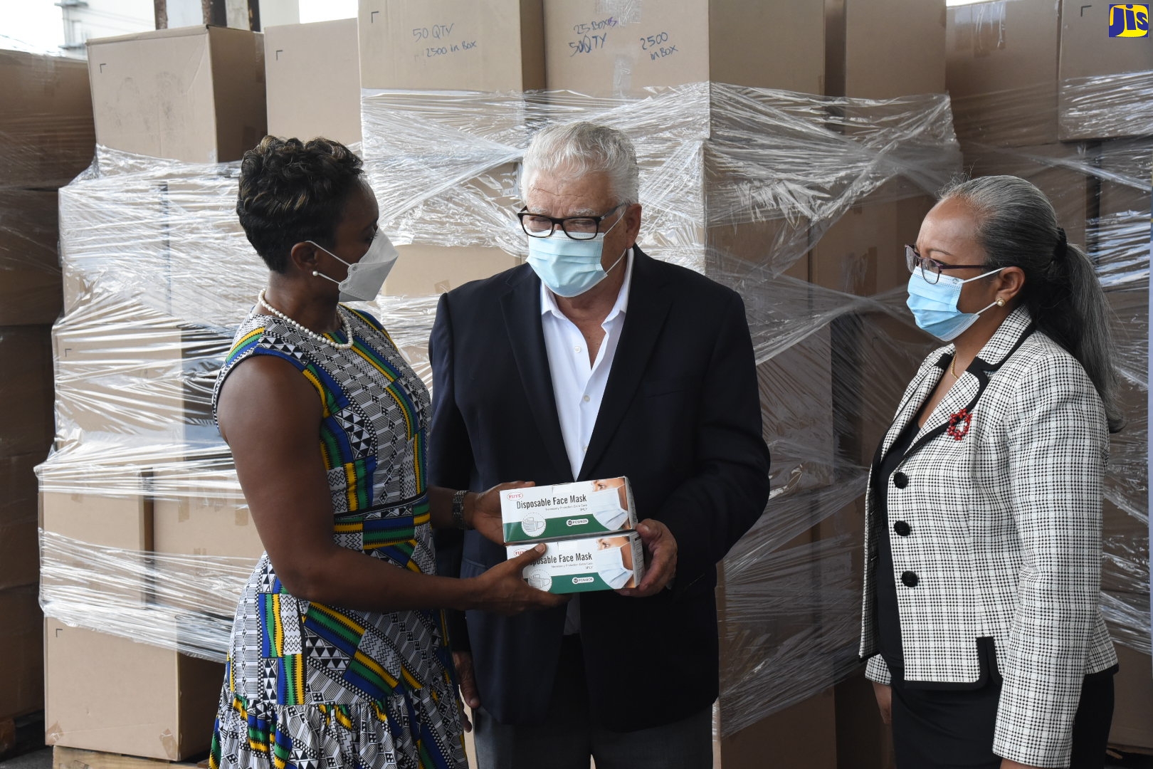 Minister of Labour and Social Security, Hon. Karl Samuda (centre), hands over two boxes of face masks to Minister of State in the Ministry of Health and Wellness, Hon. Juliet Cuthbert-Flynn (left), at the Ministry’s Marcus Garvey Drive facility in St. Andrew, recently. Looking on at right is Permanent Secretary in the Labour and Social Security Ministry, Colette Roberts Risden. The masks are part of a donation received from Atlas International Freight Forwarding Inc., to help contain the coronavirus (COVID-19).